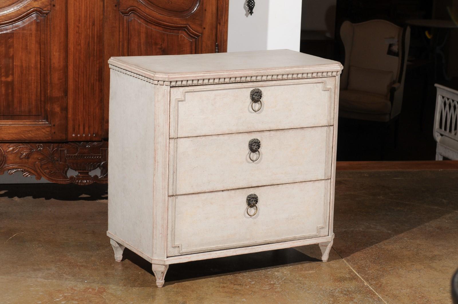 A Swedish Gustavian style painted wood three-drawer chest from the 19th century, with dentil molding and canted side posts. Born in Sweden during the 19th century, this Gustavian style painted chest features a rectangular top with canted corners in