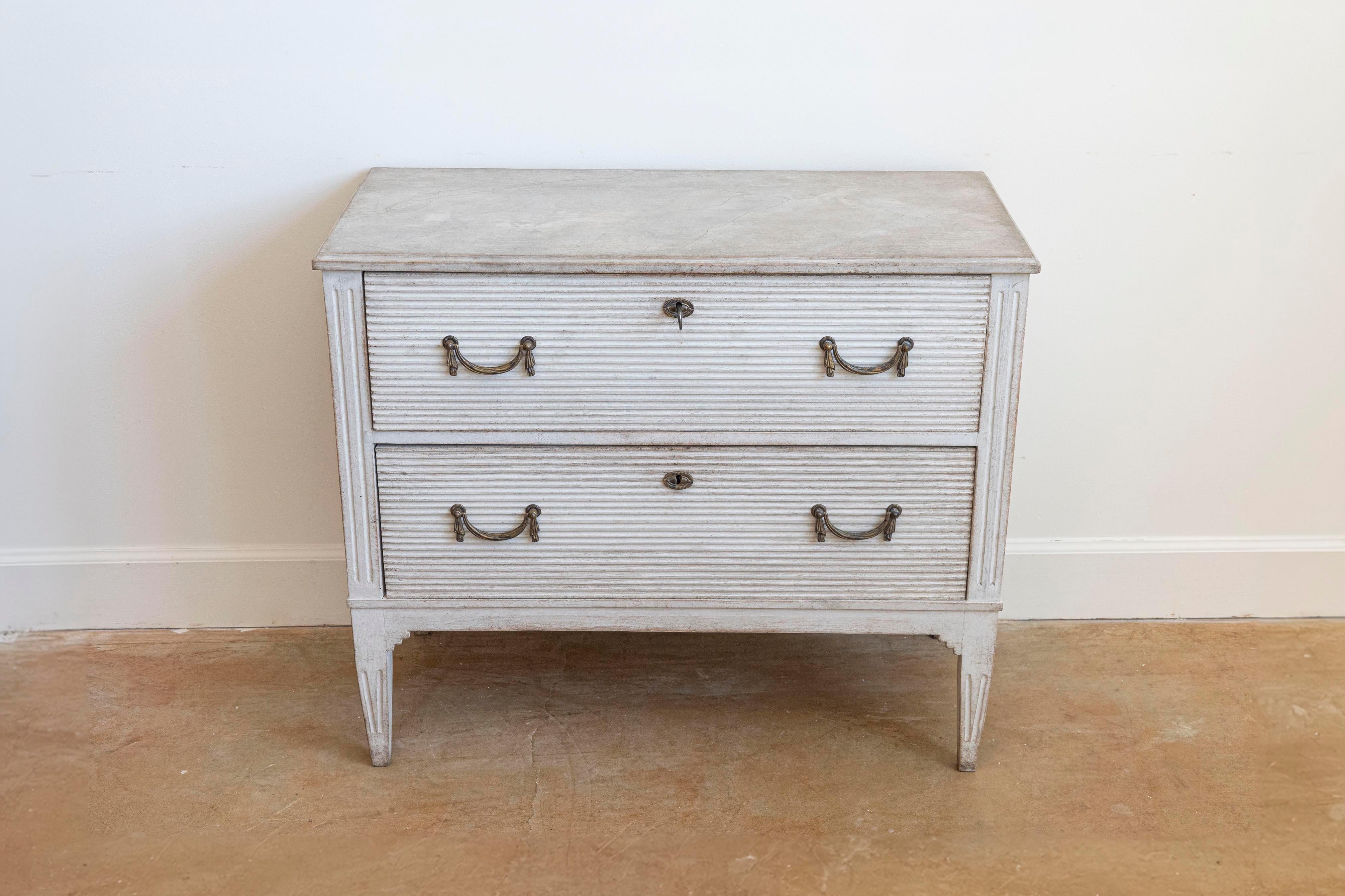 Cassapanca in legno dipinto in stile gustaviano del XIX secolo con due cassetti, accenti intagliati e ribattuti, ferramenta a scacchiera, piano marmorizzato e gambe affusolate. Creata in Svezia nel XIX secolo, questa cassapanca in legno dipinto