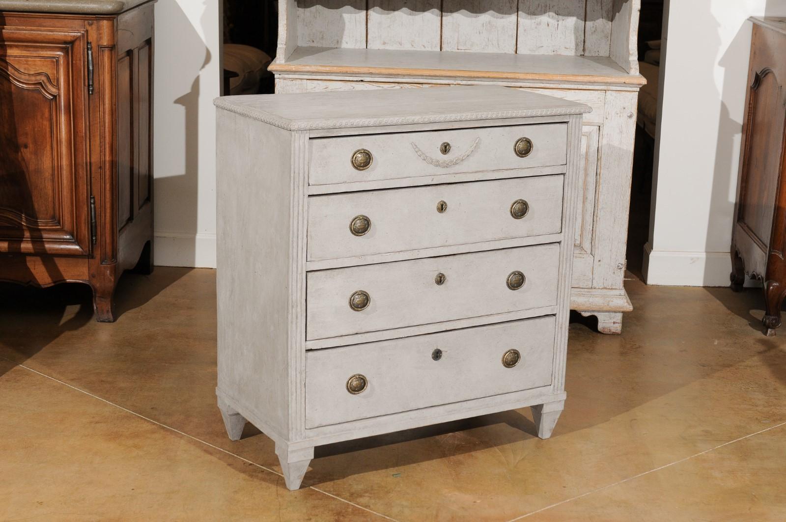 A Swedish Gustavian style painted wood chest-of-drawers from the 19th century, with carved guilloches and swag. Created in Sweden during the 19th century, this painted chest features a rectangular top carved with guilloche motifs on the rim, sitting
