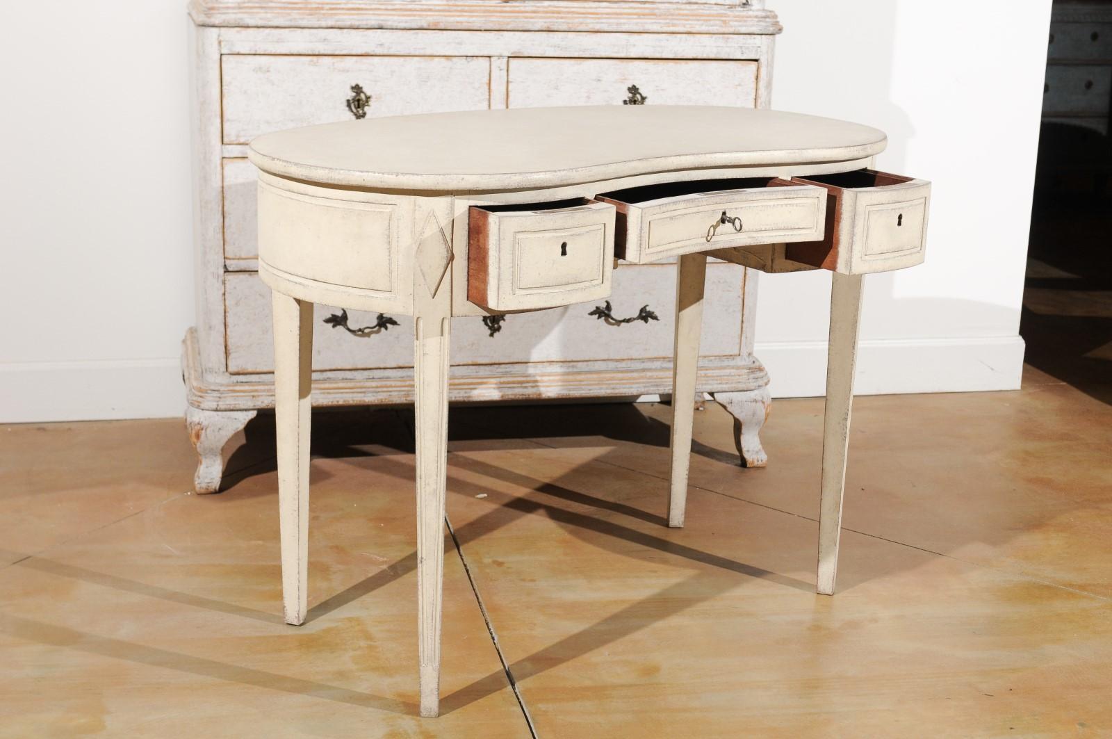 A Scandinavian Gustavian style painted wood freestanding dressing table from the 19th century, with bean-shaped top, three drawers, tapered legs and diamond motifs. Born in Sweden during the 19th century, this painted freestanding dressing table