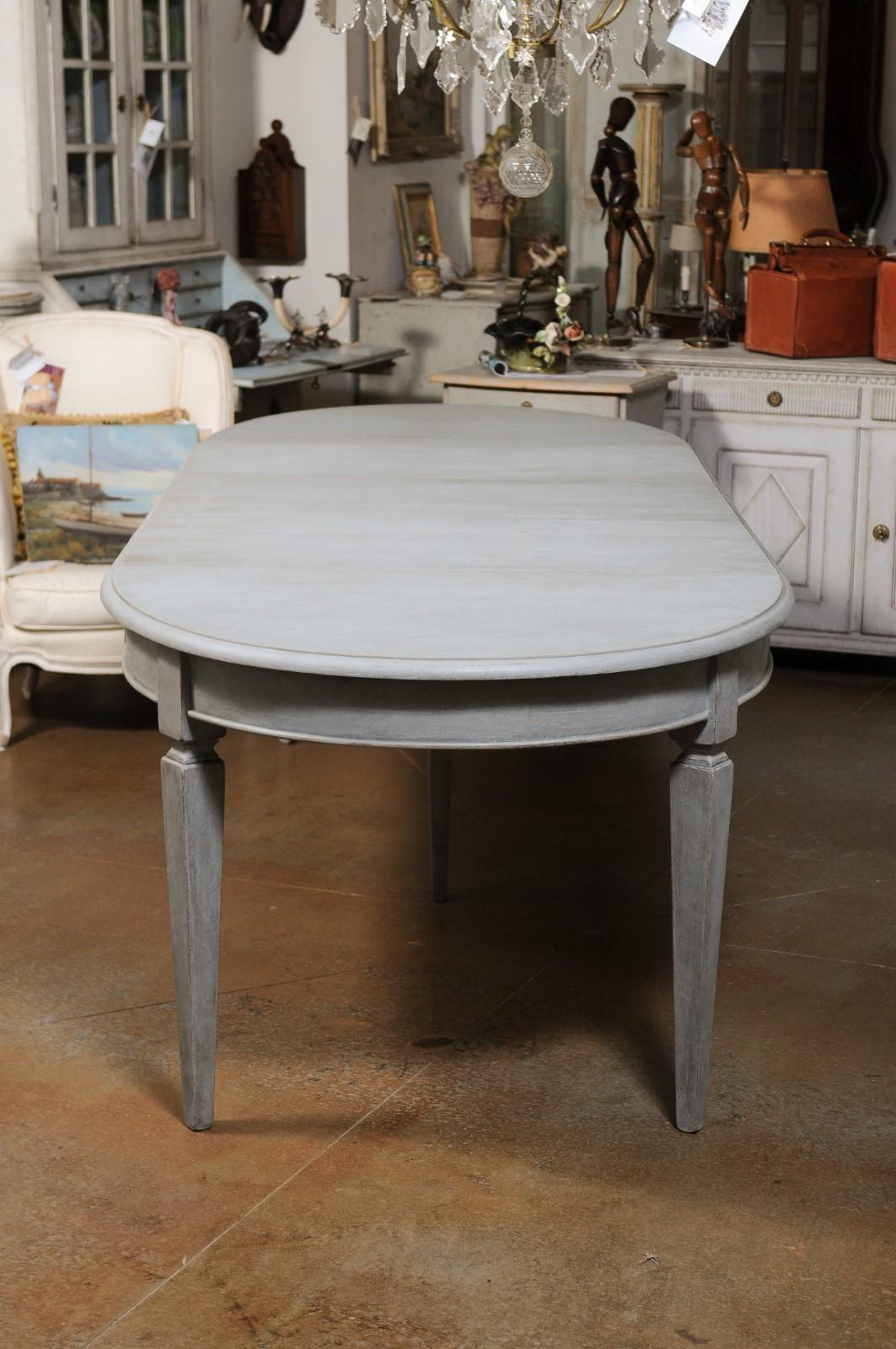 A Swedish Gustavian style painted wood extension dining room table from the early 20th century, with three new custom-made leaves. Created in Sweden during the early years of the 20th century, this Swedish dining room table features an oval top