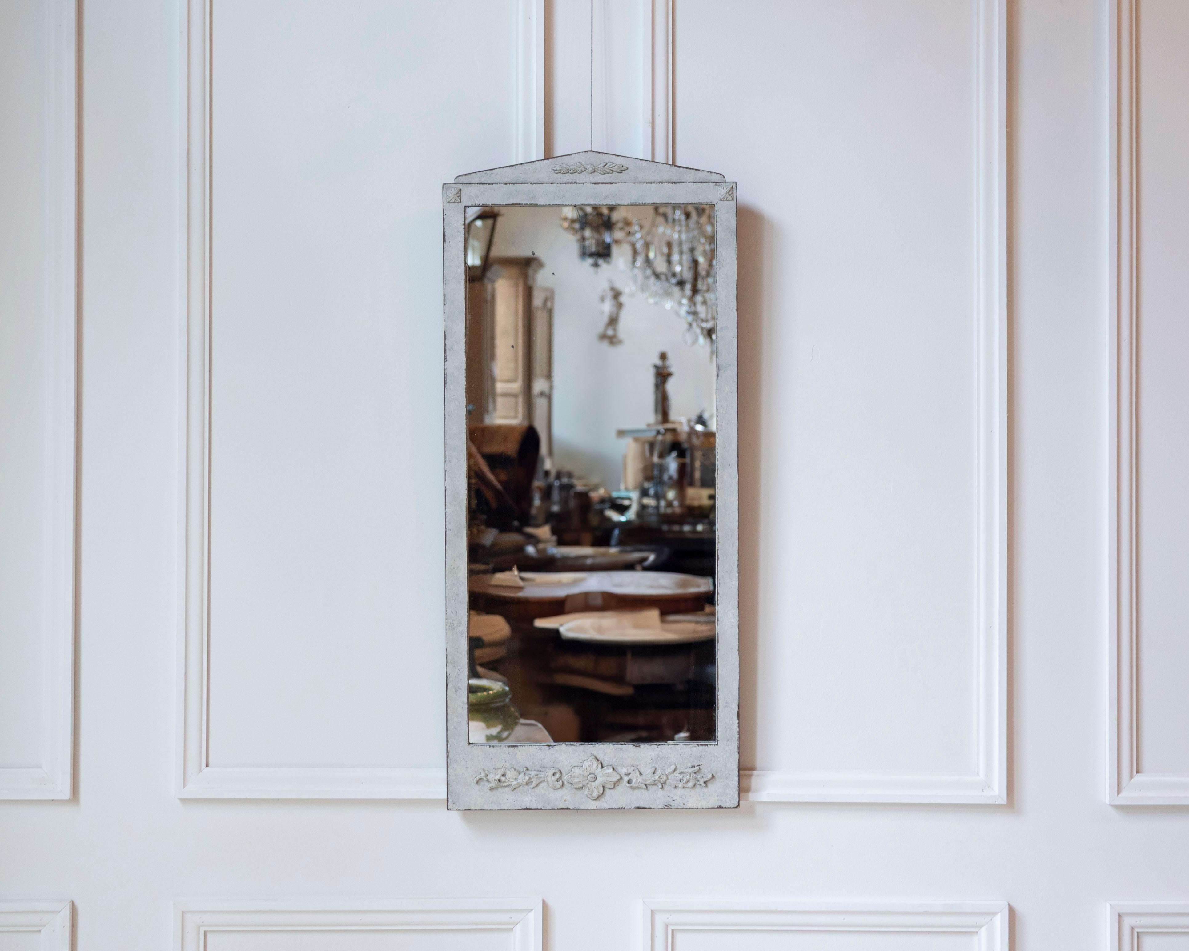 A fine Swedish mirror in the Gustavian style, dating to approximately 1920. The rectangular frame is delicately carved with understated floral and foliate motifs, reflecting the graceful simplicity and neoclassical influence characteristic of