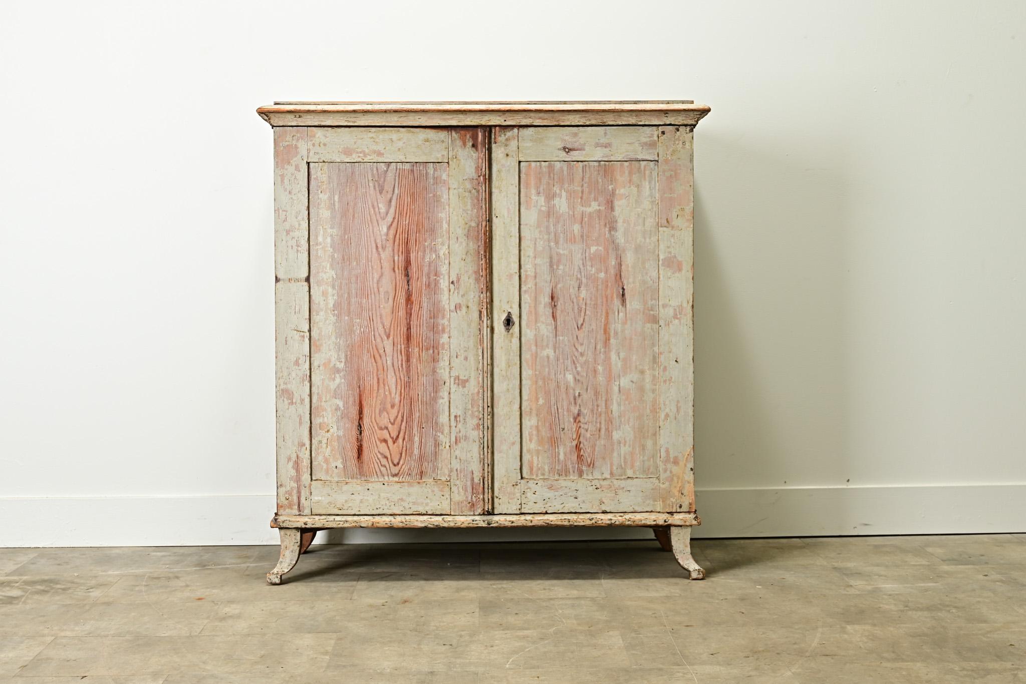 A Swedish Gustavian style cabinet with its original worn paint finish. Made of solid pine, this buffet is sturdy and functional. The pair of paneled doors open to a fitted interior with three drawers and two 15” deep fixed shelves. Be sure to view
