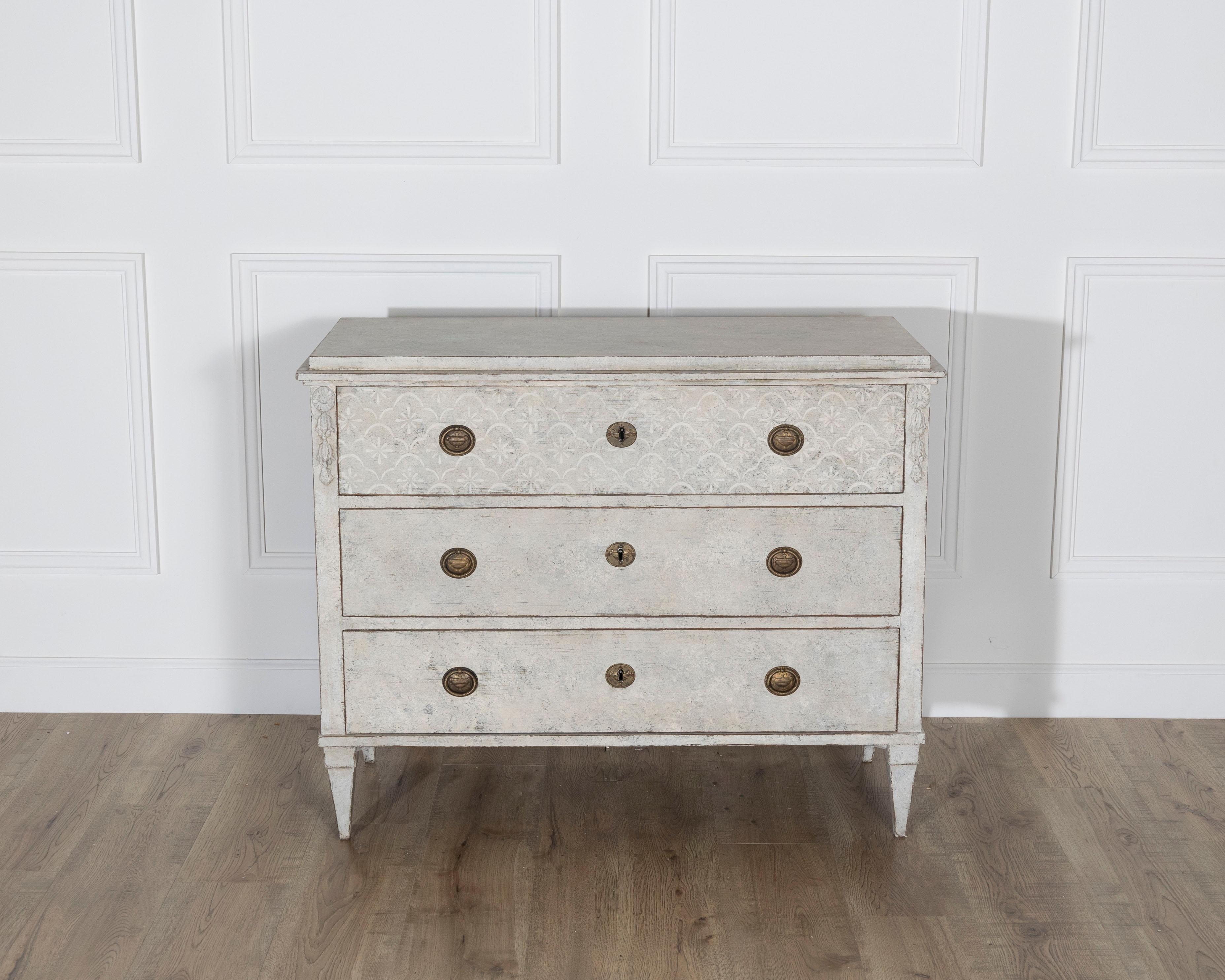This exquisite Gustavian style chest of drawers, dating to around 1840, exemplifies the refined elegance and balanced proportions of Swedish neoclassical design. Painted in a soft light sand hue with a beautifully aged finish, it features three