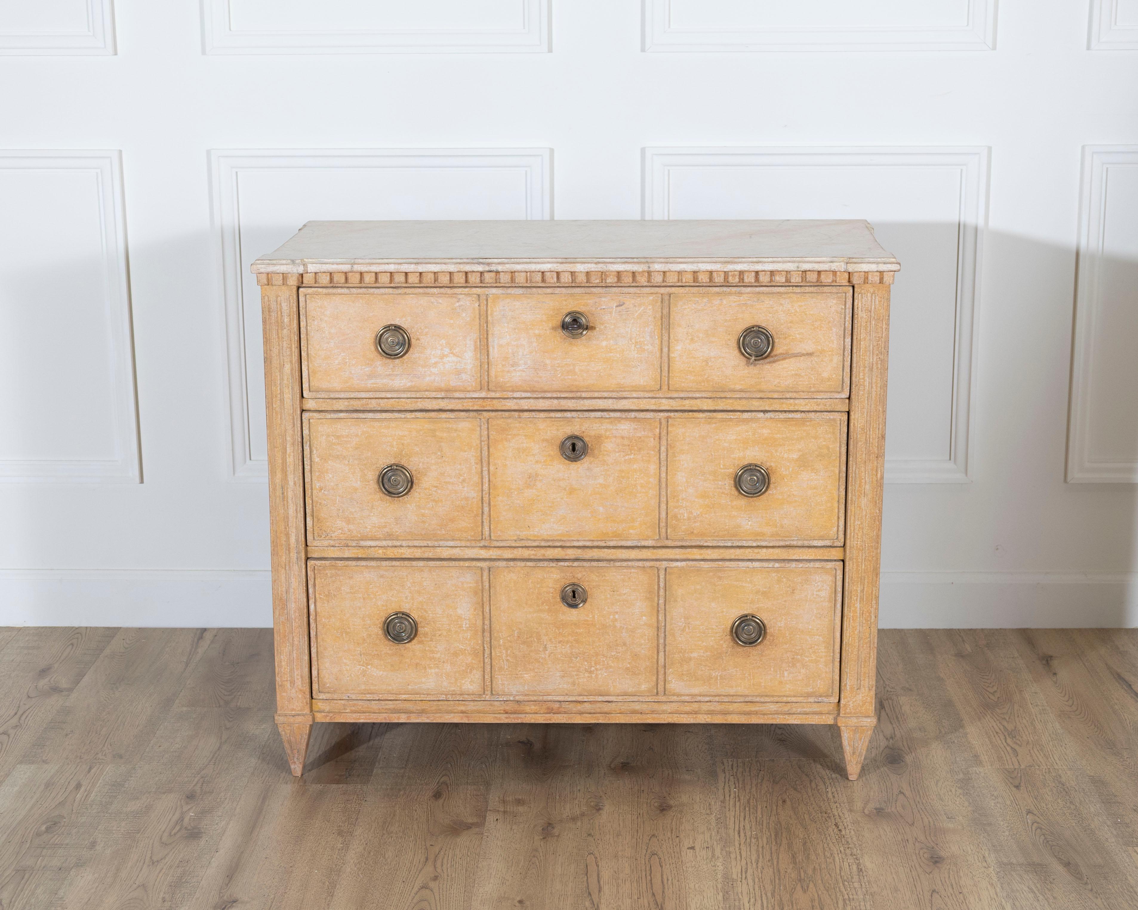 Una cassettiera svedese in stile gustaviano realizzata nel 1890-1900 circa, che si distingue per la calda tonalità terra di Siena e il piano marmorizzato dipinto a mano. La sottile imitazione del marmo aggiunge profondità e raffinatezza alla