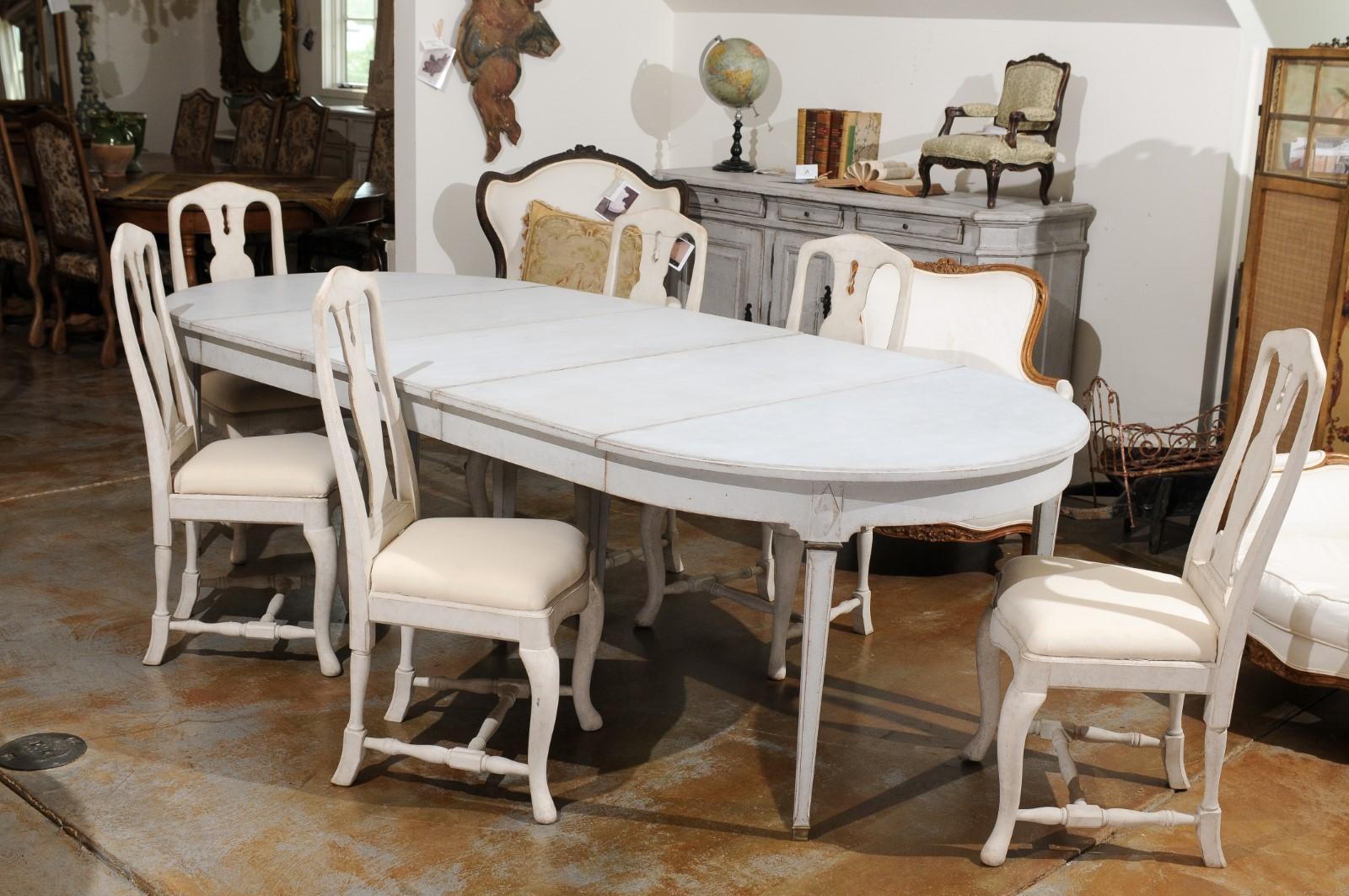 A Swedish Gustavian style painted wood extension dining room table from the 19th century, with carved diamond motifs, brass accents and three new leaves. Created in Sweden during the 19th century, this Swedish dining room table features an oval top