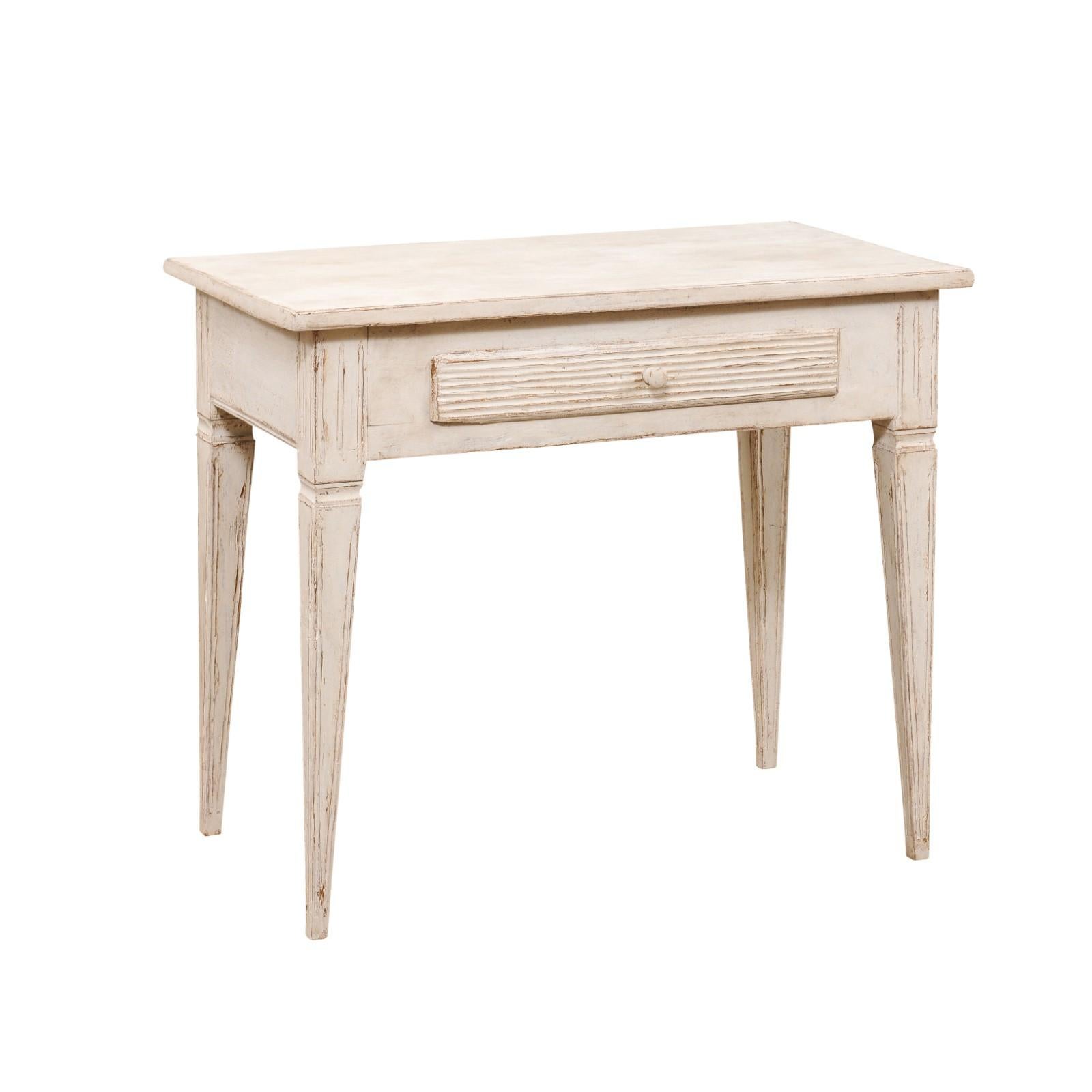 A Swedish Gustavian style painted wood side table from the late 19th century, with single drawer, reeded accents and tapered legs. Created in Sweden during the last quarter of the 19th century, this side table features a rectangular top sitting