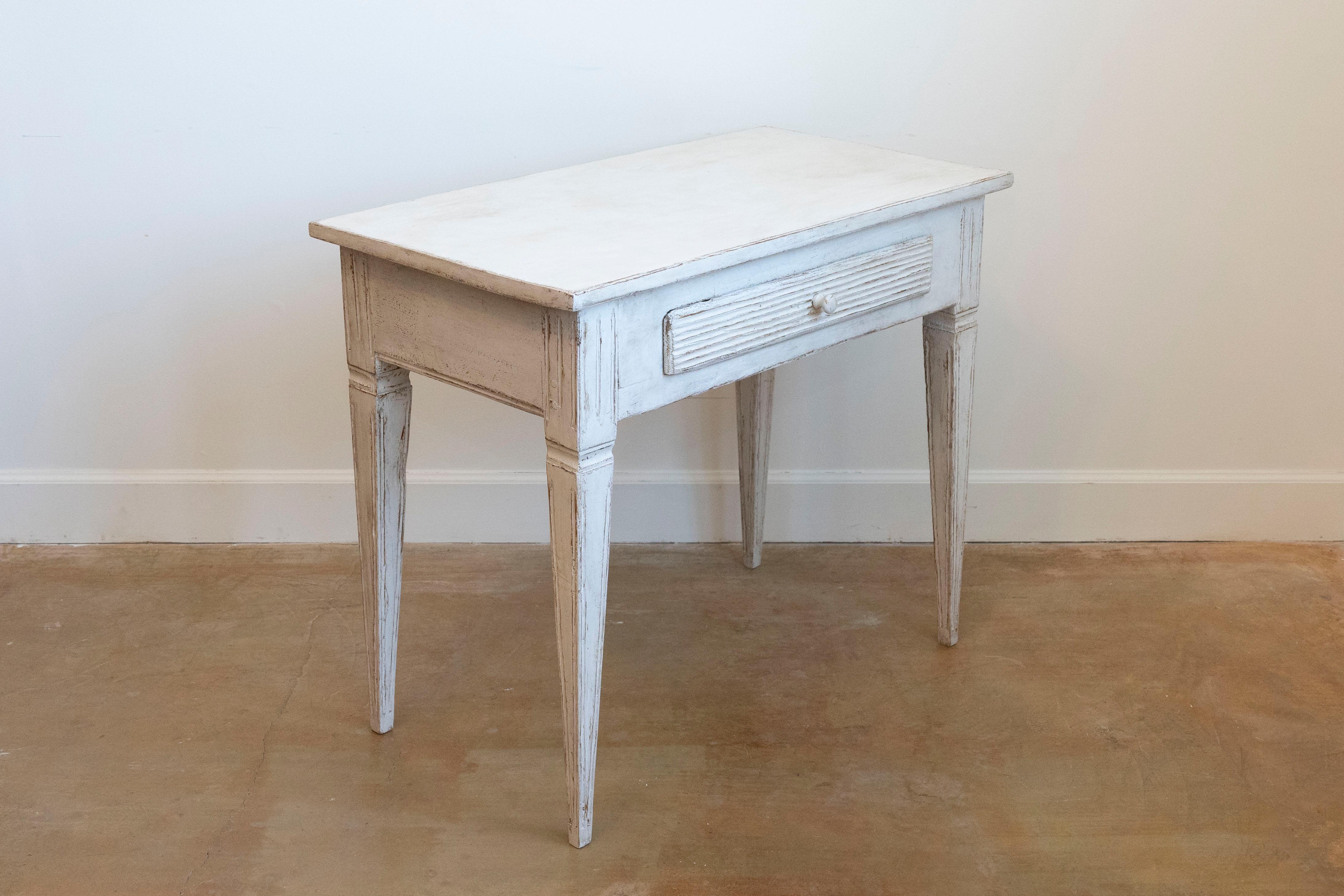 A Swedish Gustavian style painted wood side table from the late 19th century, with single drawer, reeded accents and tapered legs. Created in Sweden during the last quarter of the 19th century, this side table features a rectangular top sitting