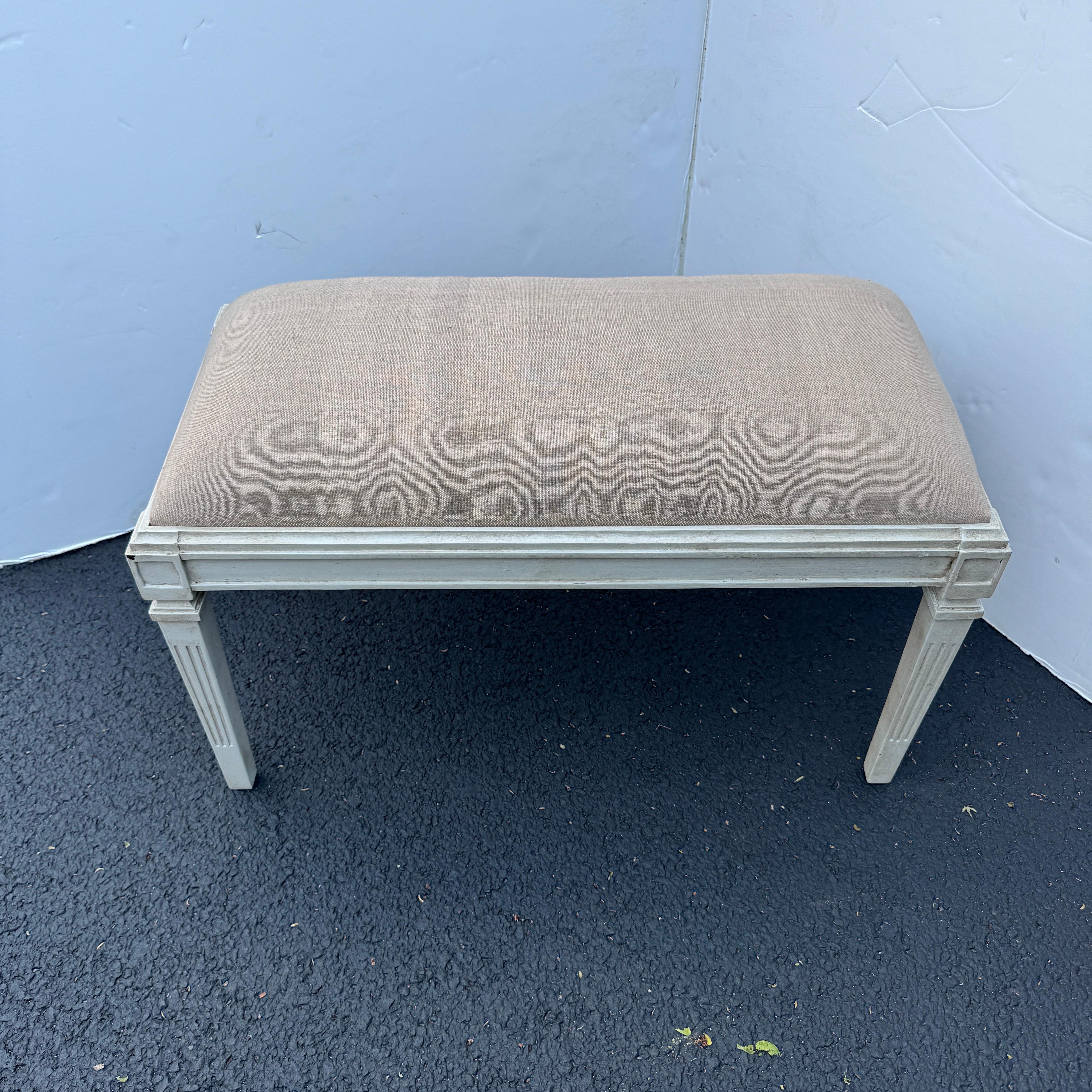 Swedish Gustavian Style Painted Upholstered Bench. Hand painted and hand distressed wood bench fully upholstered in a neutral linen textile. Wonderful addition to any style home, used formally or informally in an entrance area, living room or