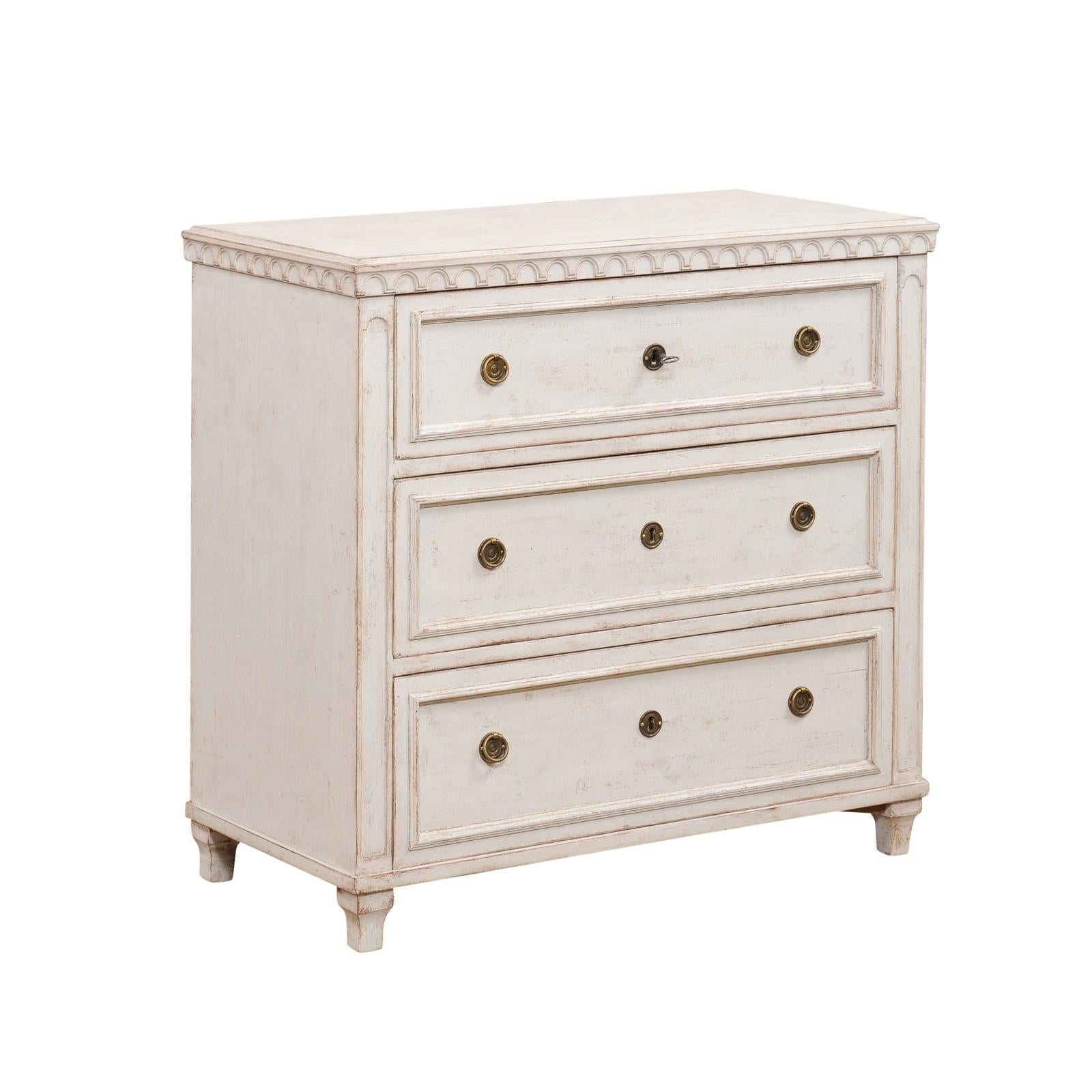 A Swedish Gustavian style painted wood chest from the late 19th century, with three graduated drawers, carved motifs and brass hardware. Created in Sweden during the last decade of the 19th century, this three-drawer chest showcases the stylistic