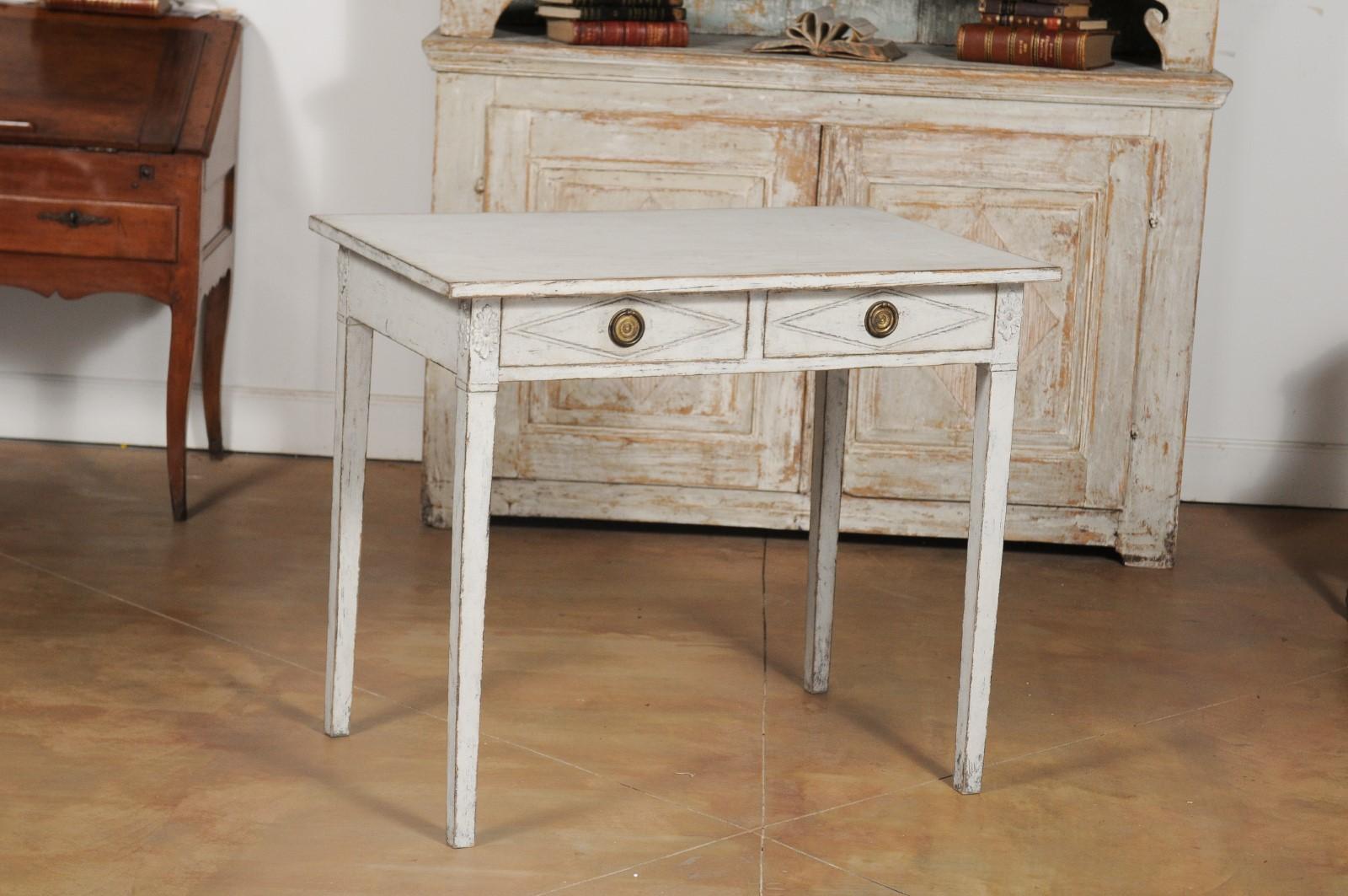 A Swedish Gustavian Style painted wood desk from the 20th century, with two drawers, diamond motifs and carved rosettes. Born in Sweden during the 20th century, this painted desk features a rectangular top sitting above two drawers, each carved with