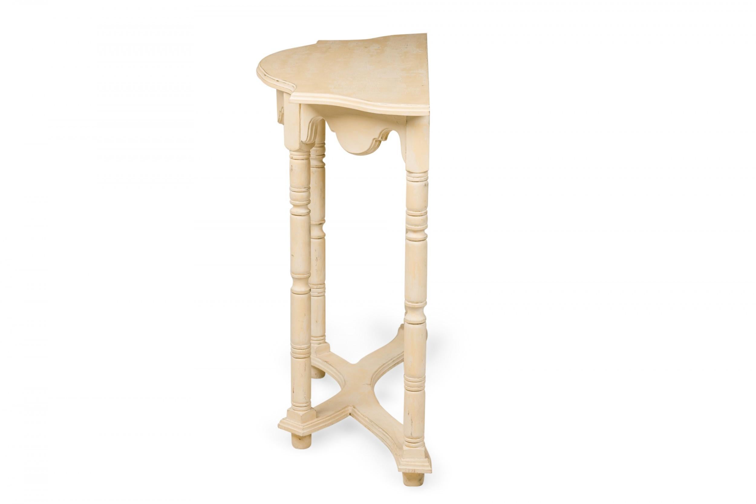 Consola demiluna sueca de estilo Gustaviano (s. XX) con tablero perfilado y faldón con bordes biselados, apoyada en cuatro patas torneadas con base de camilla en forma de X, pintada de amarillo pálido.

Pérdidas en el acabado pintado.