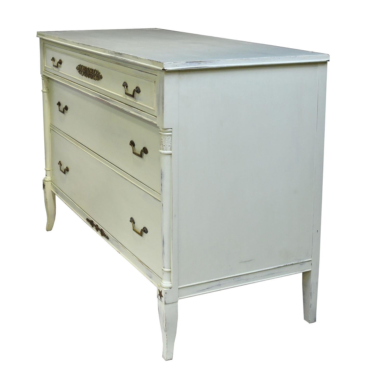 A charming Swedish Gustavian-style/ Empire-style chest in a painted light-pastel green finish, with three long storage drawers of staggered depths. All parts of the chest of drawers are made of solid mahogany (except for the back) & features lovely