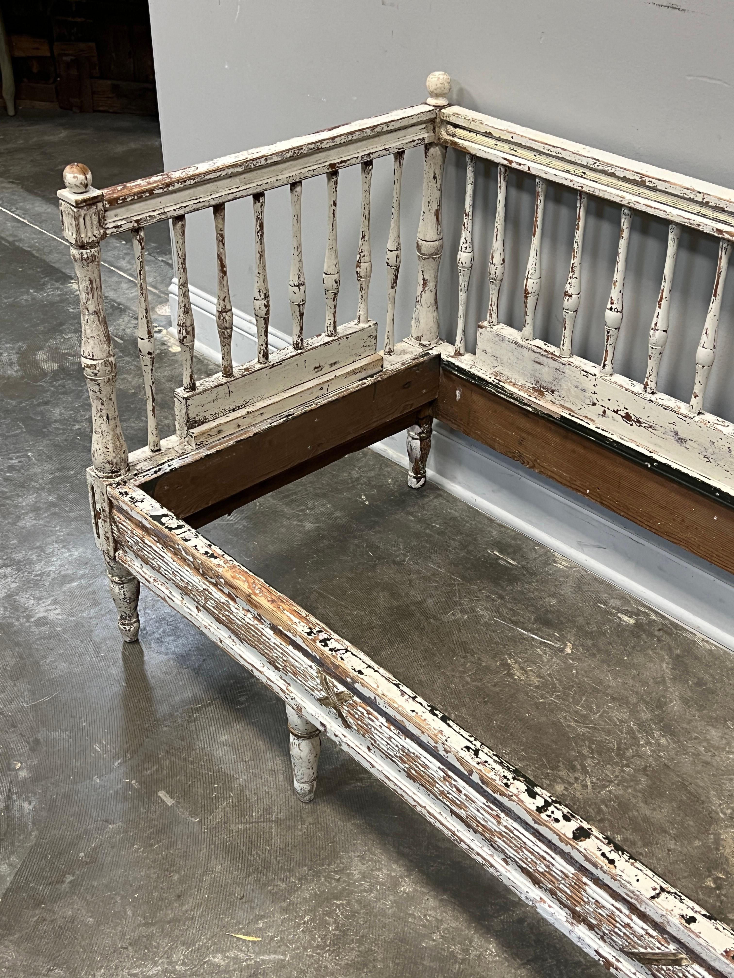 Early Swedish settee in the Gustavian style which echoes the Louis XVI style in France. The influence of the French style is further evidence with subtle banded and ribboned decorations on the end and cross traverses and turned Louis XVI style legs.