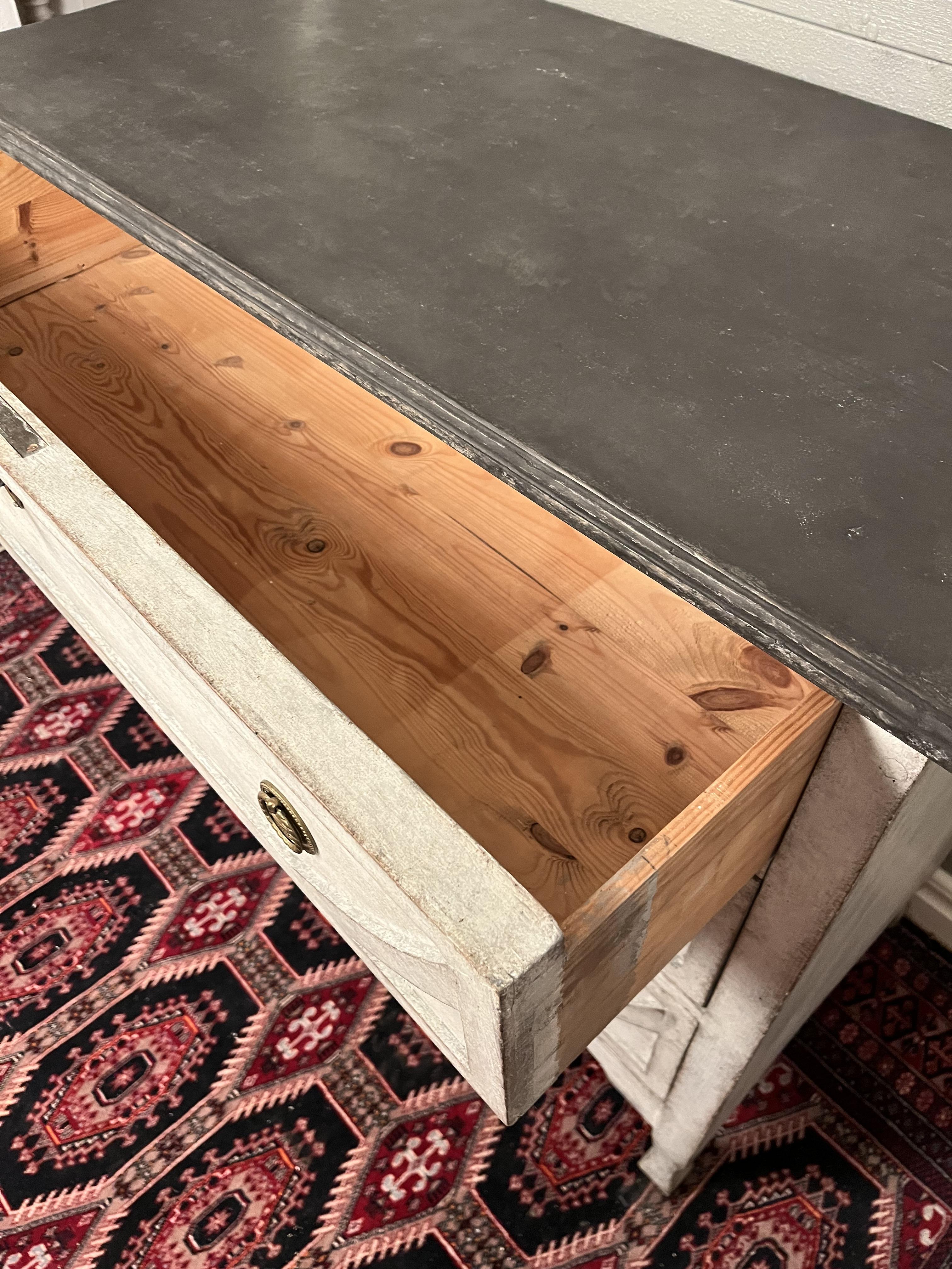 A Swedish Gustavian style painted wood chest from the early 20th century with three drawers. 

Painted in grey with black top and a beautiful distressed patina look
Classical brass hardwear on every drawer

This Swedish Gustavian style three-drawer