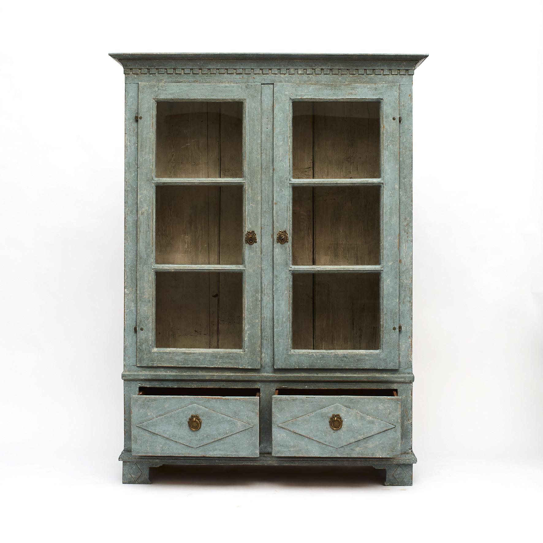 Swedish Gustavian style vitrine/display cabinet.
Pair of paned glass doors, the inside with upright partition in the middle dividing the cabinet into two interior sections of storage, with shelves on each side.
Cornice featuring carved dentil