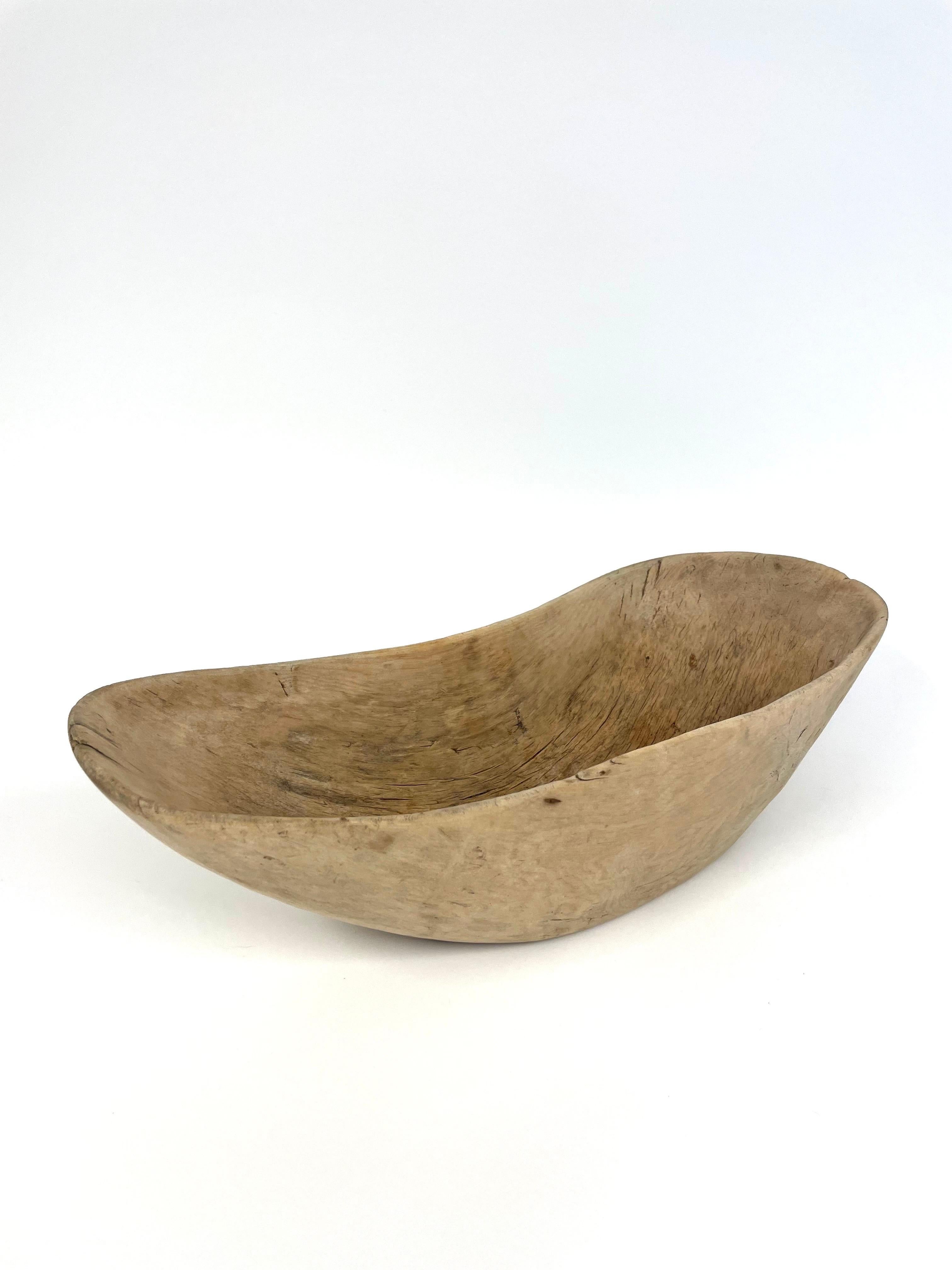 This is a beautiful Swedish hand-carfted, carved 19th century wooden bowl in Wabi Sabi style. 
It comes made in an oblong piece of pine, perhaps a thin trunk but more likely a thick branch given the slightly curved shape. Either way, the curved
