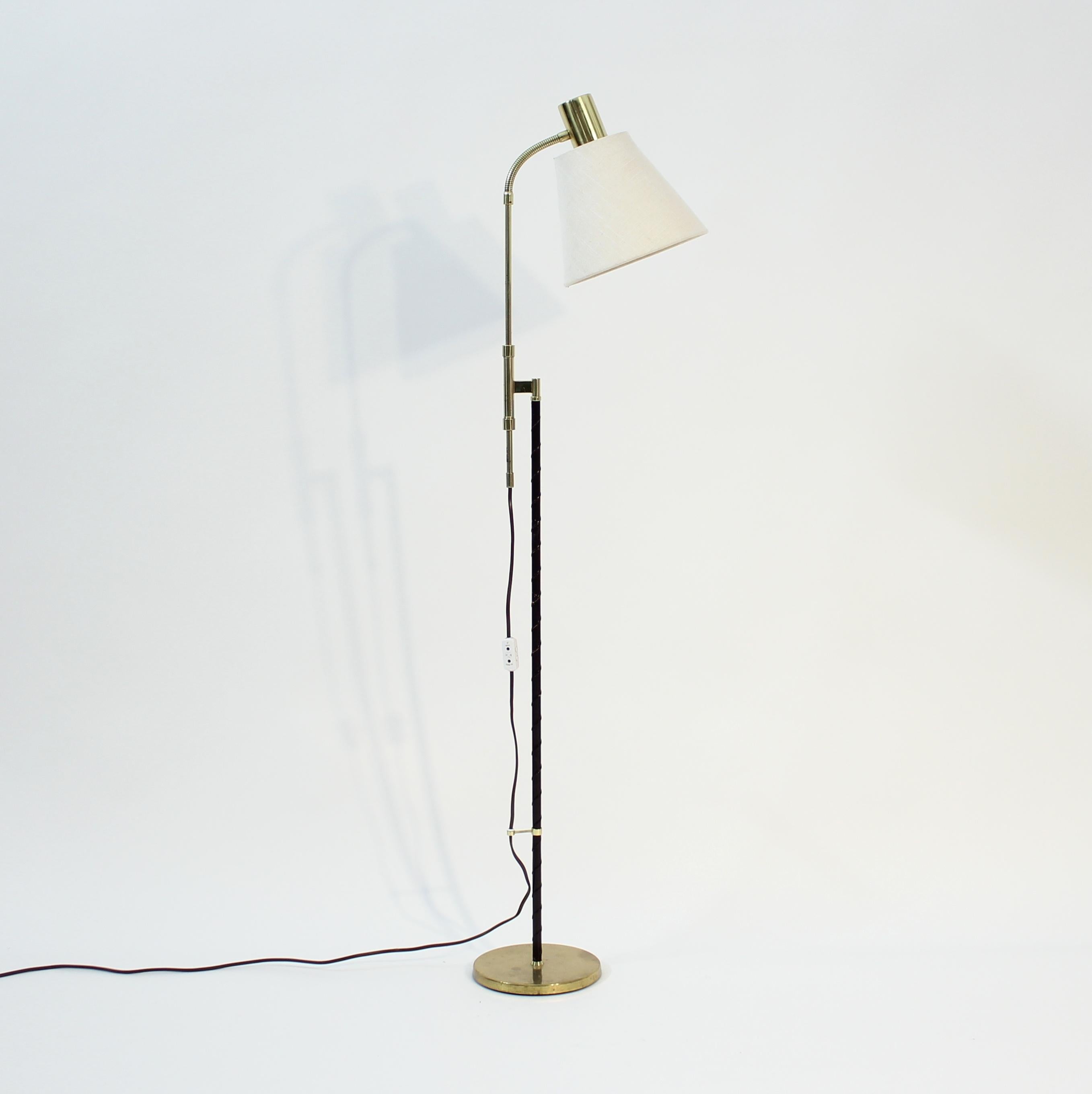 Swedish mid-century floor lamp by MAE (Möller Armatur Eskilstuna) with a leather covered brass stem on a round brass base. Off-white fabric shade. Height adjustable between 112-138 cm. Good vintage condition with light ware consistent with age and