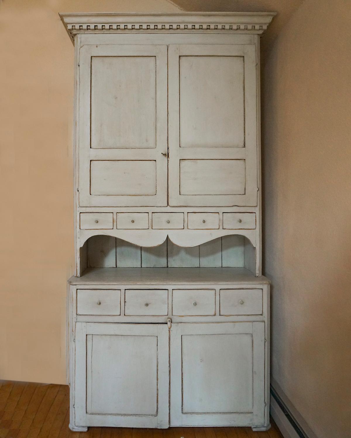 Two part cabinet or hutch, Sweden circa 1820, with serving space. The upper section has a straight cornice with dental detail over a pair of paneled doors and row of small drawers. The interior has two fixed shelves. Paneled back and nicely curved