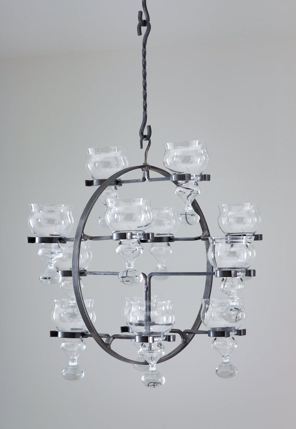 Hanging candelabra in wrought iron and crystal by Bertil Vallien for Boda Smide, Sweden, circa 1970.
It consists of 12 candleholders held by a circular wrought iron frame.
Condition: Very good original condition.