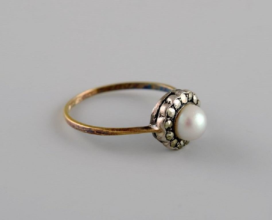 Swedish jeweler. Vintage art deco ring in 18-carat gold adorned with cultured pearl and marcasite stones. 
1920s / 30s.
Diameter: 17.5 mm.
US size: 7.25.
In excellent condition.
Stamped.
In most cases, we can change the size for a fee (USD 50) per