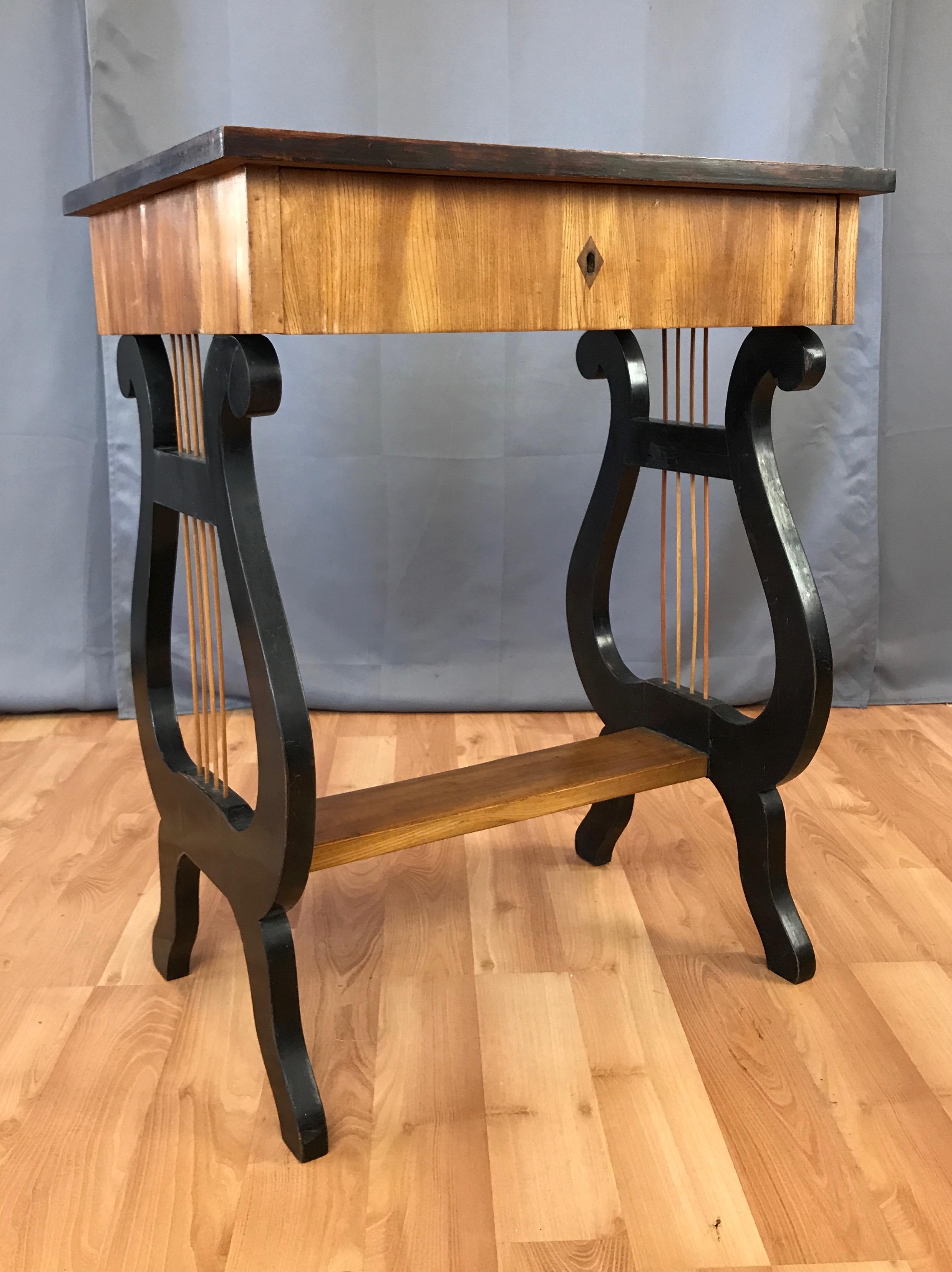 An early Karl Johan-period Swedish Biedermeier lyre motif small birch table with drawer.

Bookmatched birch veneer top with ebonized edge, and birch veneer sides and drawer with diamond keyhole. (Key no longer extant.) Originally designed as a
