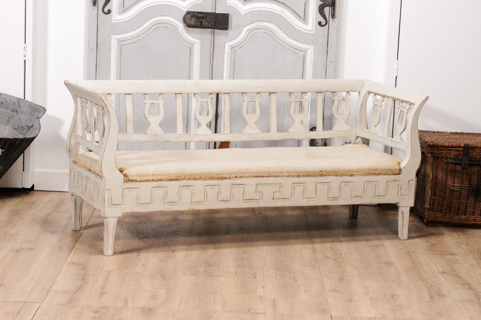 A Swedish Karl Johan period painted wood sofa from circa 1820 with carved lyres, out-scrolling arms, meander frieze and tapered legs. Step into the elegant period of Karl Johan with this beautifully crafted Swedish painted wood sofa from circa 1820.