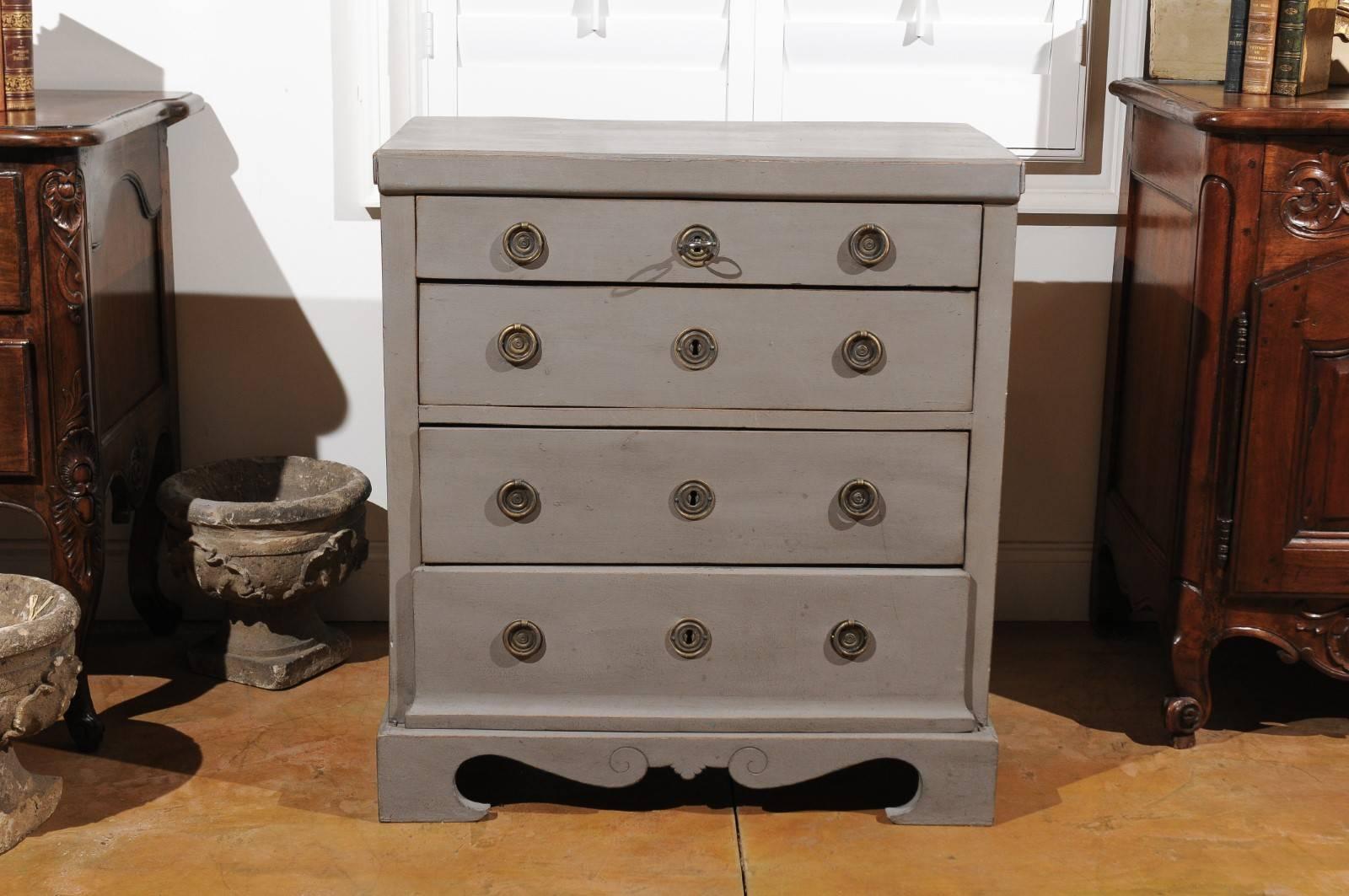 A Swedish Karl Johan period painted wood four-drawer commode from the first half of the 19th century, with bracket feet and voluted skirt. This Swedish painted commode features a rectangular, slightly raised top, sitting above four graduated