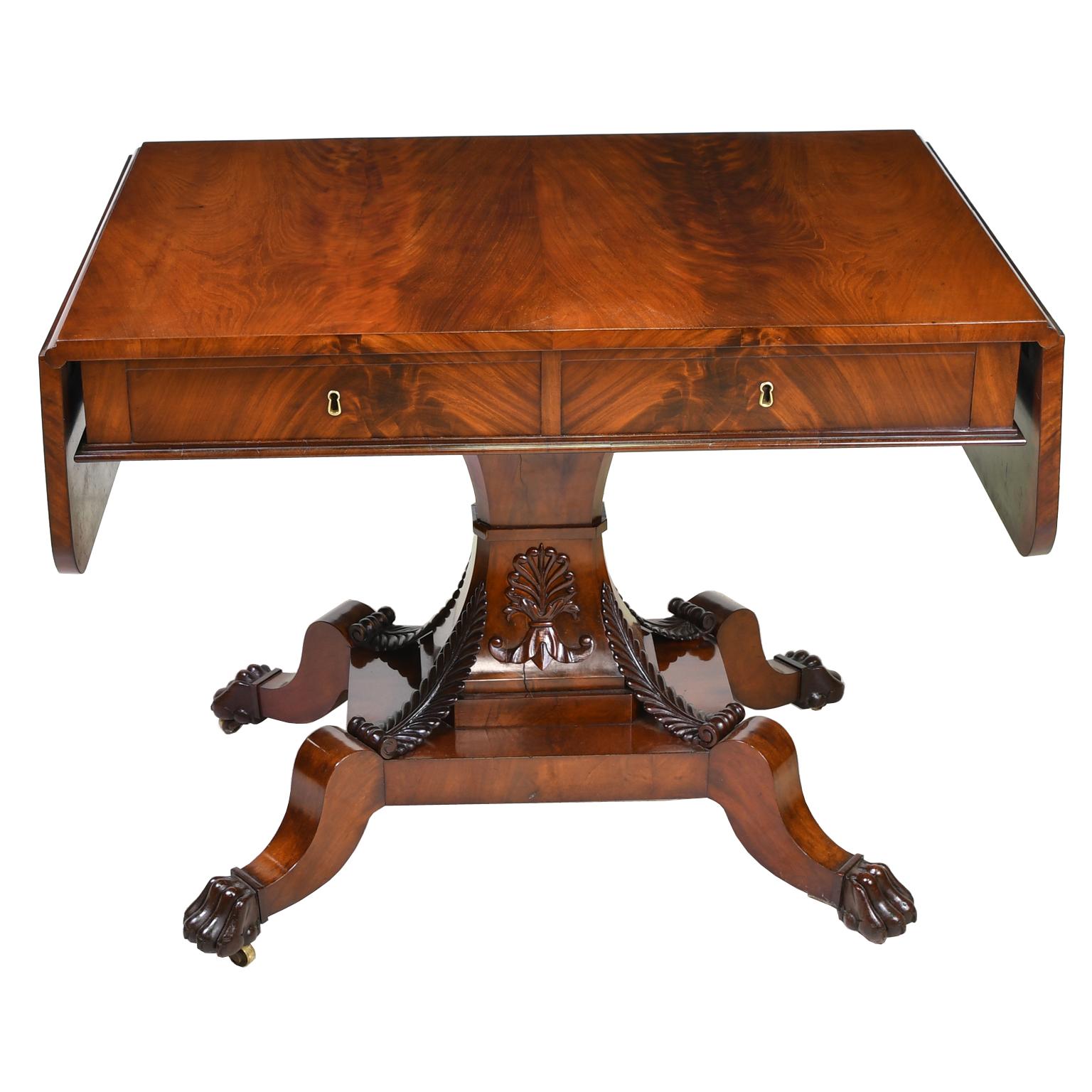 An exceptionally fine Karl Johan salon table, sofa table or desk in beautiful West Indies mahogany. The top has two leaves that drop down on each side with two drawers along the apron, and is supported by a center pedestal composed of a concave