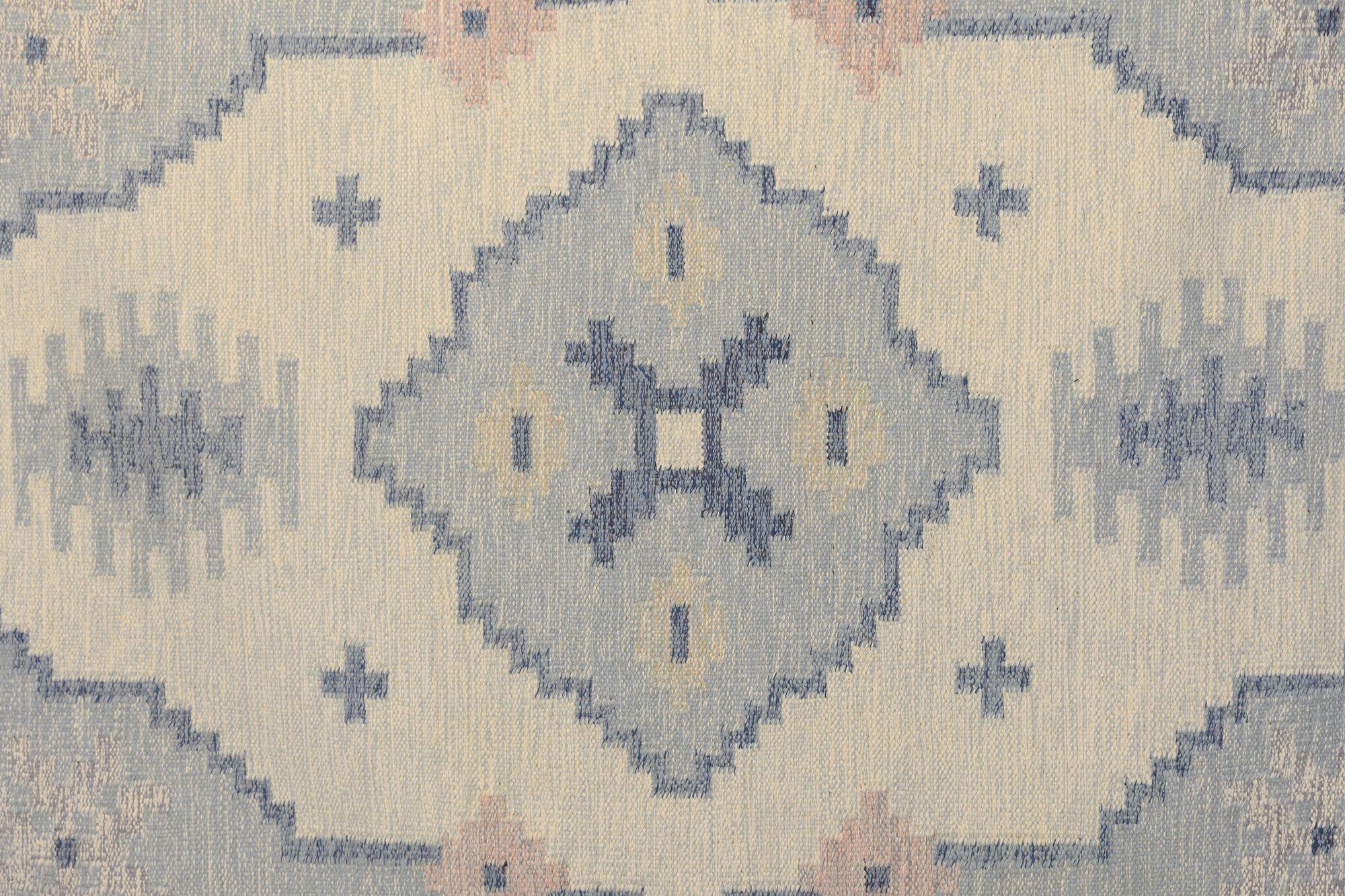 Schwedischer Kelim aus der Mitte des Jahrhunderts mit persischem Einfluss in Blau-, Creme- und Rosatönen. Gezeichnet E.S. Schweden um 1960. Alle unsere Teppiche werden einer professionellen Reinigung unterzogen. Aufgrund ihres Alters und ihres