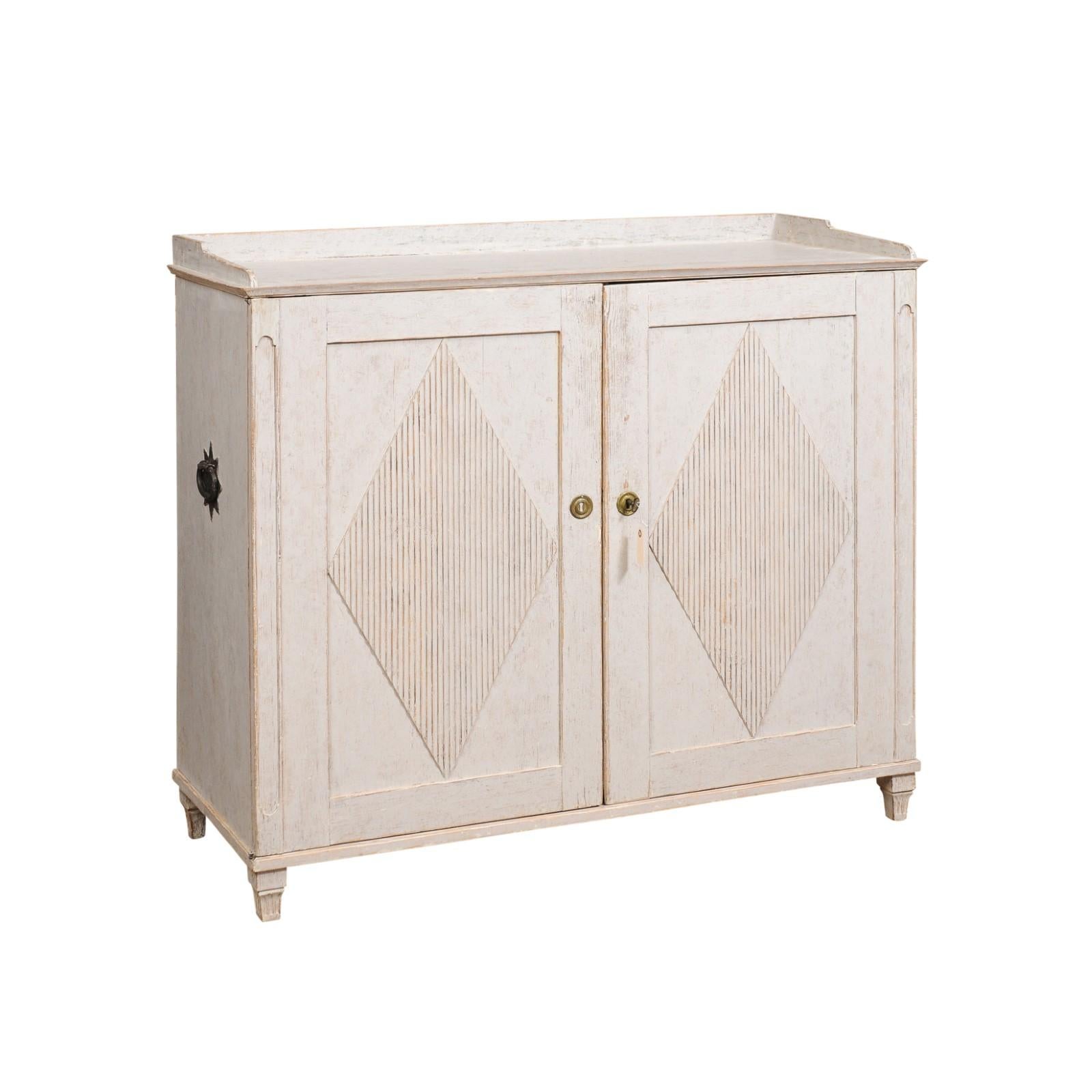 A Swedish Gustavian period painted wood sideboard from the early 19th century with carved diamond motifs. This Swedish Gustavian period sideboard, crafted in the first quarter of the 19th century, exudes the timeless elegance and refined simplicity
