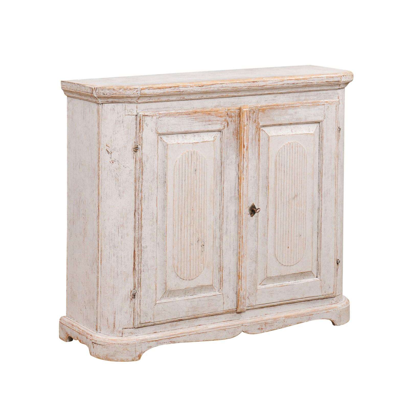 A Swedish late Gustavian period painted wood buffet from the early 19th century, with canted sides, two doors, reeded panels and weathered patina. Created in Sweden during the first quarter of the 19th century, this painted buffet features a