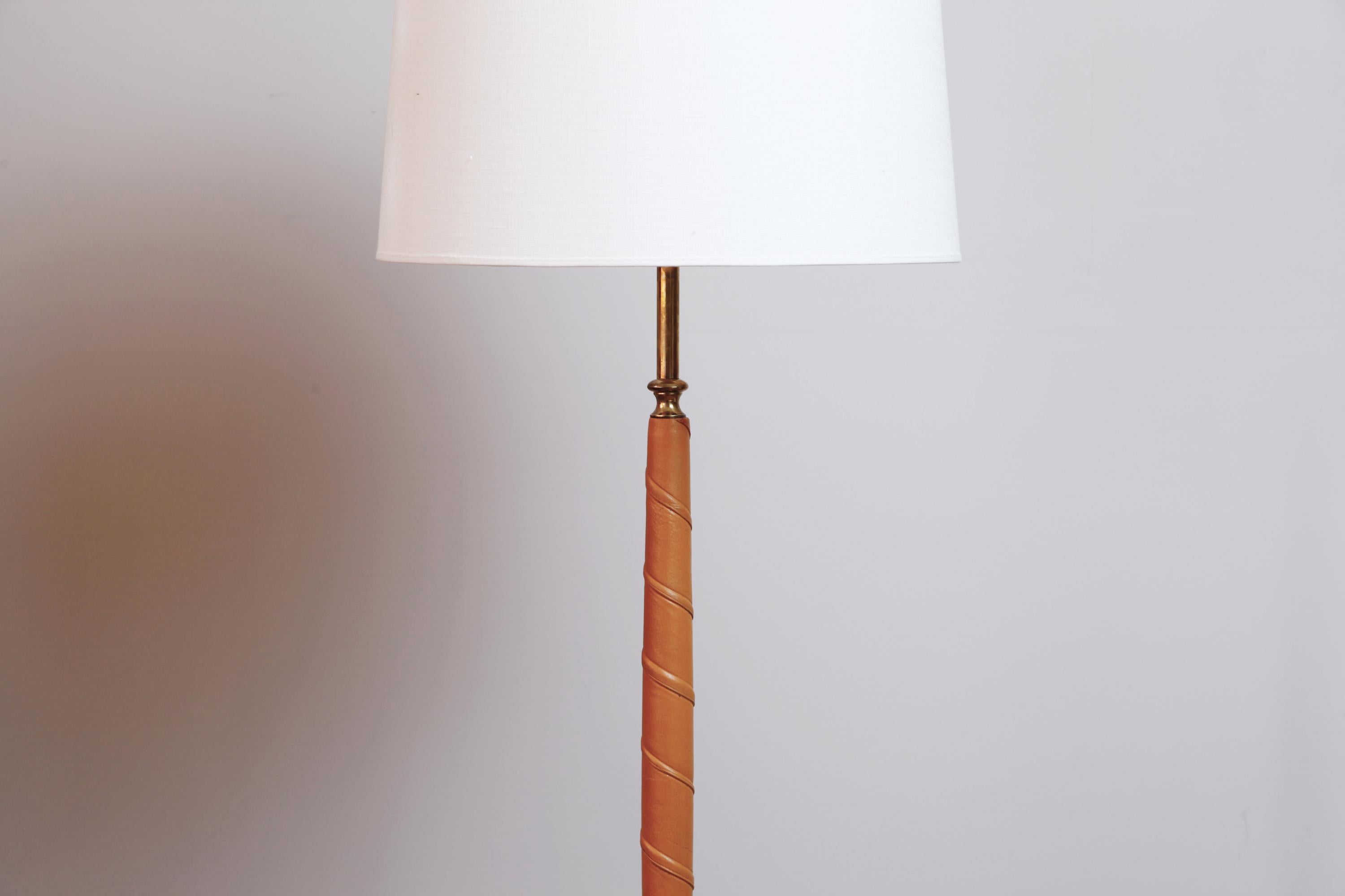 A clean-lined and elegant standing lamp, the leather-wrapped post curving slightly outward toward the middle, in the manner of a Greek Hellenistic period column, and terminating in a brass base.

Rewired for the U.S., shade included. Dimensions of