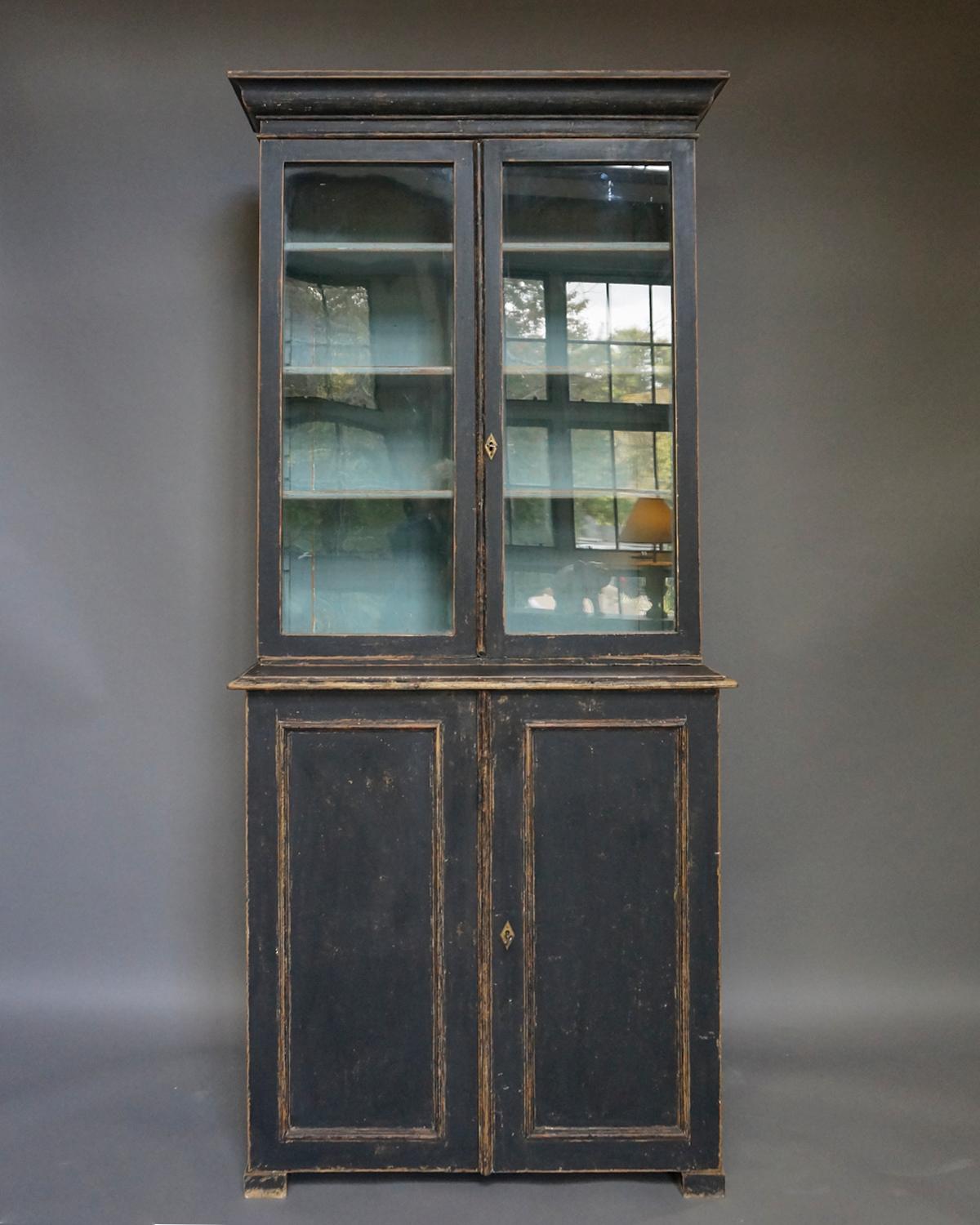 Simple Swedish two-part library cabinet, circa 1880. The double glass doors in the upper section open onto three adjustable shelves. The lower section has another two shelves behind a pair of recessed panel doors, all on low block feet.