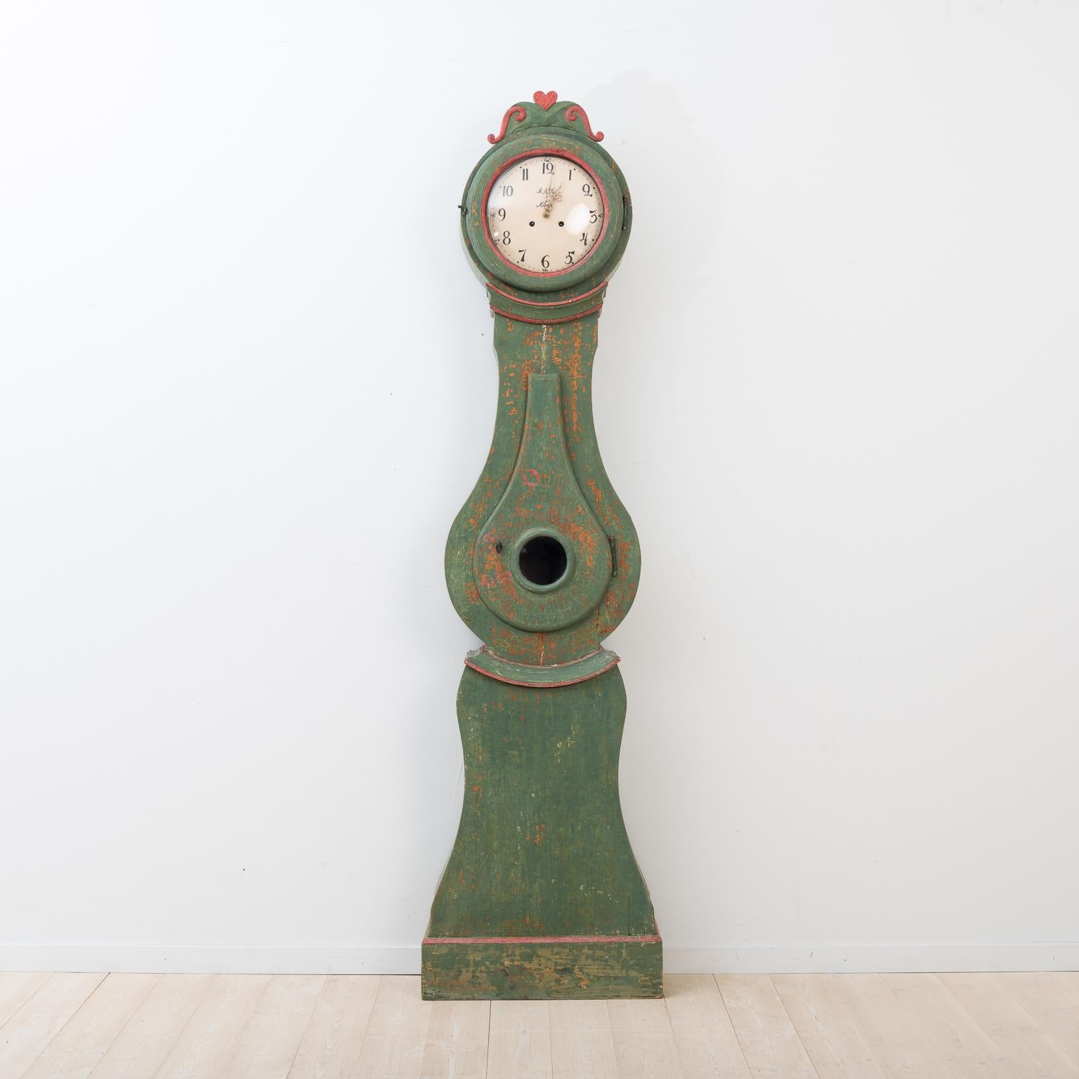 Swedish long case Rococo clock model 1820. Green original paint. 
There are minor dry cracks above and under the door. 

The clock comes with the original clockwork, two iron weights and pendulum. The clockwork has not been serviced and is sold