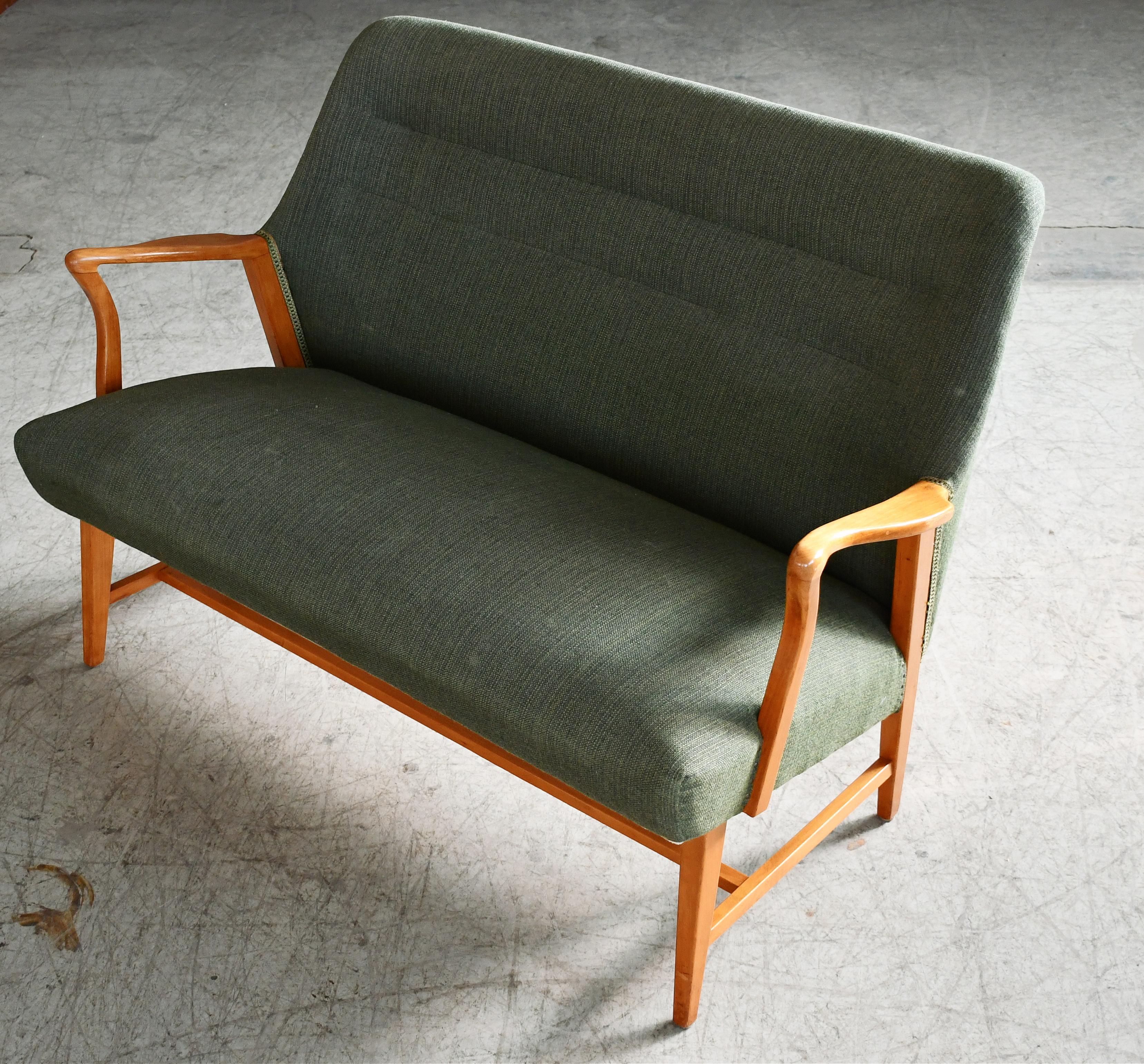 Superb Swedish settee from the late 1940's or early 1950s with coil springs in the seat and beautiful open armrests and legs carved in solid blond Elm wood with great grain and patina. We just love the simple yet very refined elegant design of this