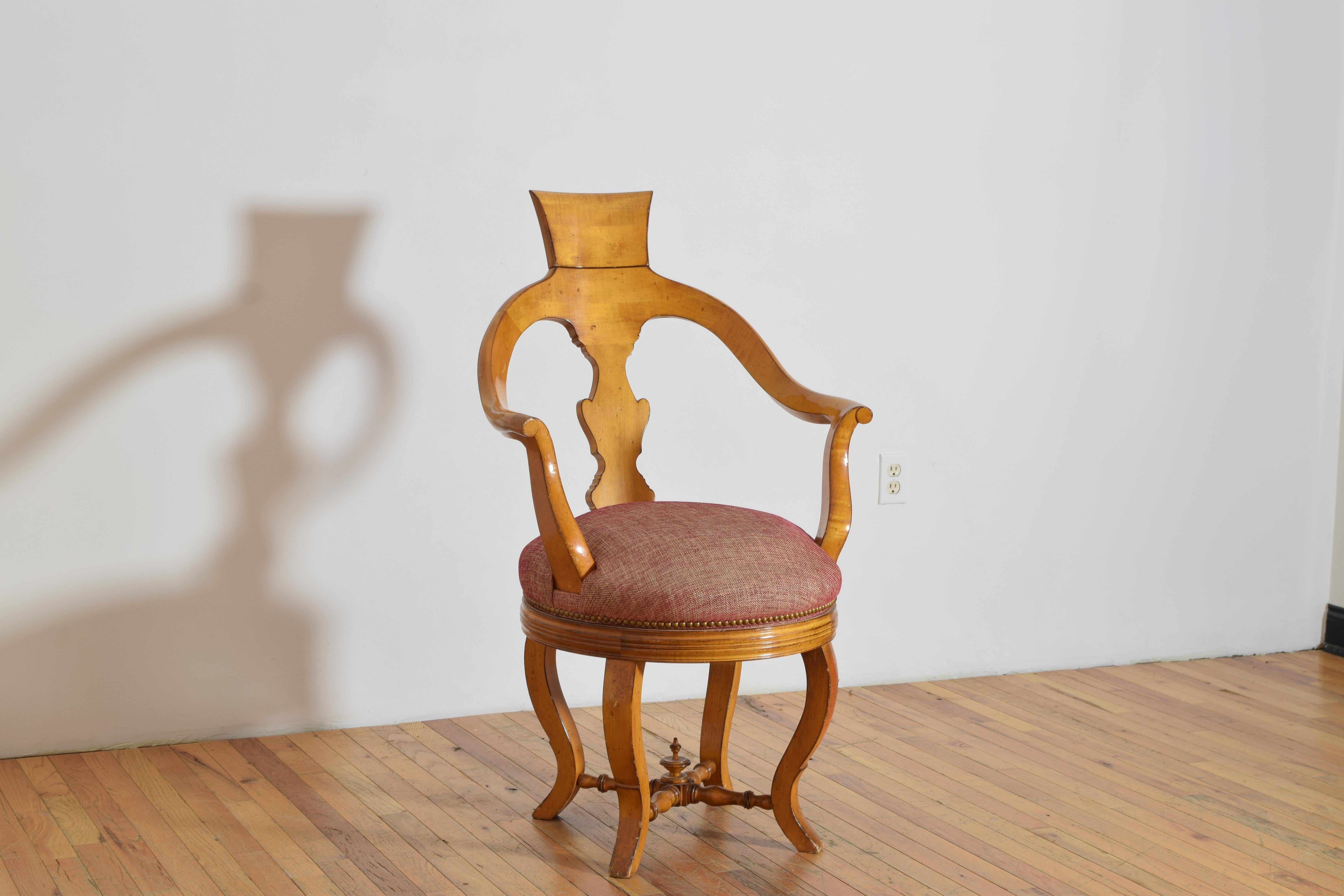 Having an open backrest with a urn-shaped splat, the top of the backrest with a folding headrest, the curved armrests above a circular seat, the upper section swiveling atop cabriole form legs joined by turned stretchers and a centered finial