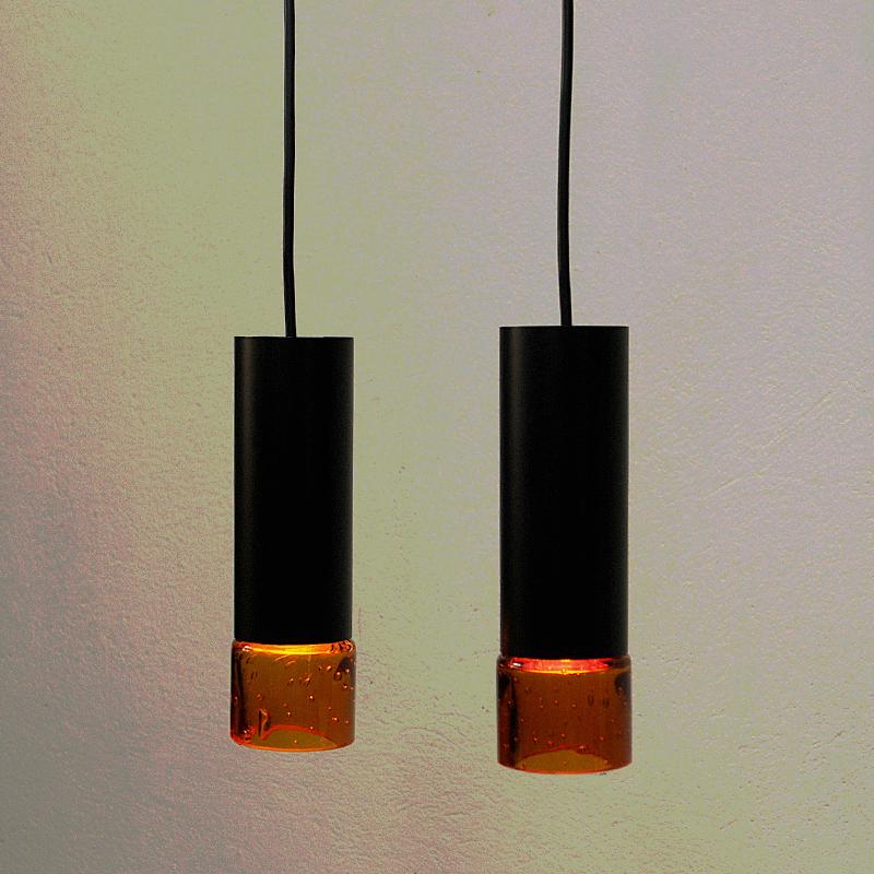 Lovely Swedish midcentury pair of pendants to be used both as ceiling -and windowlamps. Pendants from the 1960s. Looks even great over a kitchen island or table. The lamps have a black metal cylinder base with beautiful golden glass shade cups