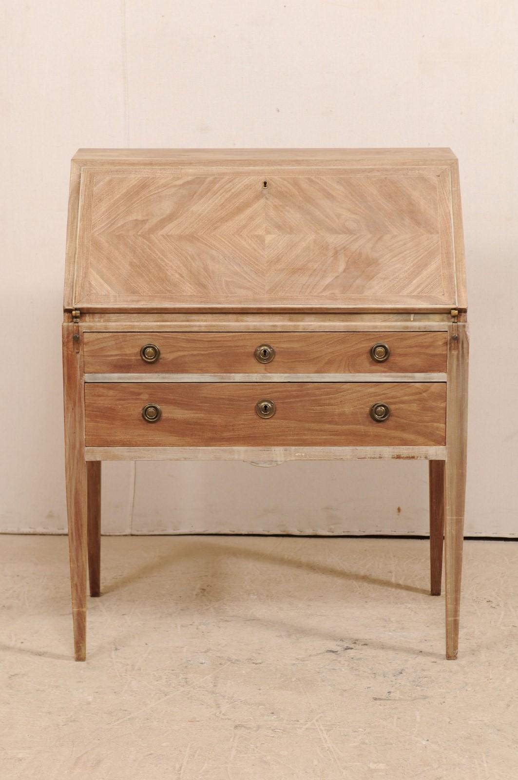 A Swedish drop-leaf secretary from the mid-20th century. This Swedish slant-top writing desk, with it's simplistic and clean design, features a top leaf which folds down to reveal smaller drawers an open, center cubby hole. When this leaf is opened,