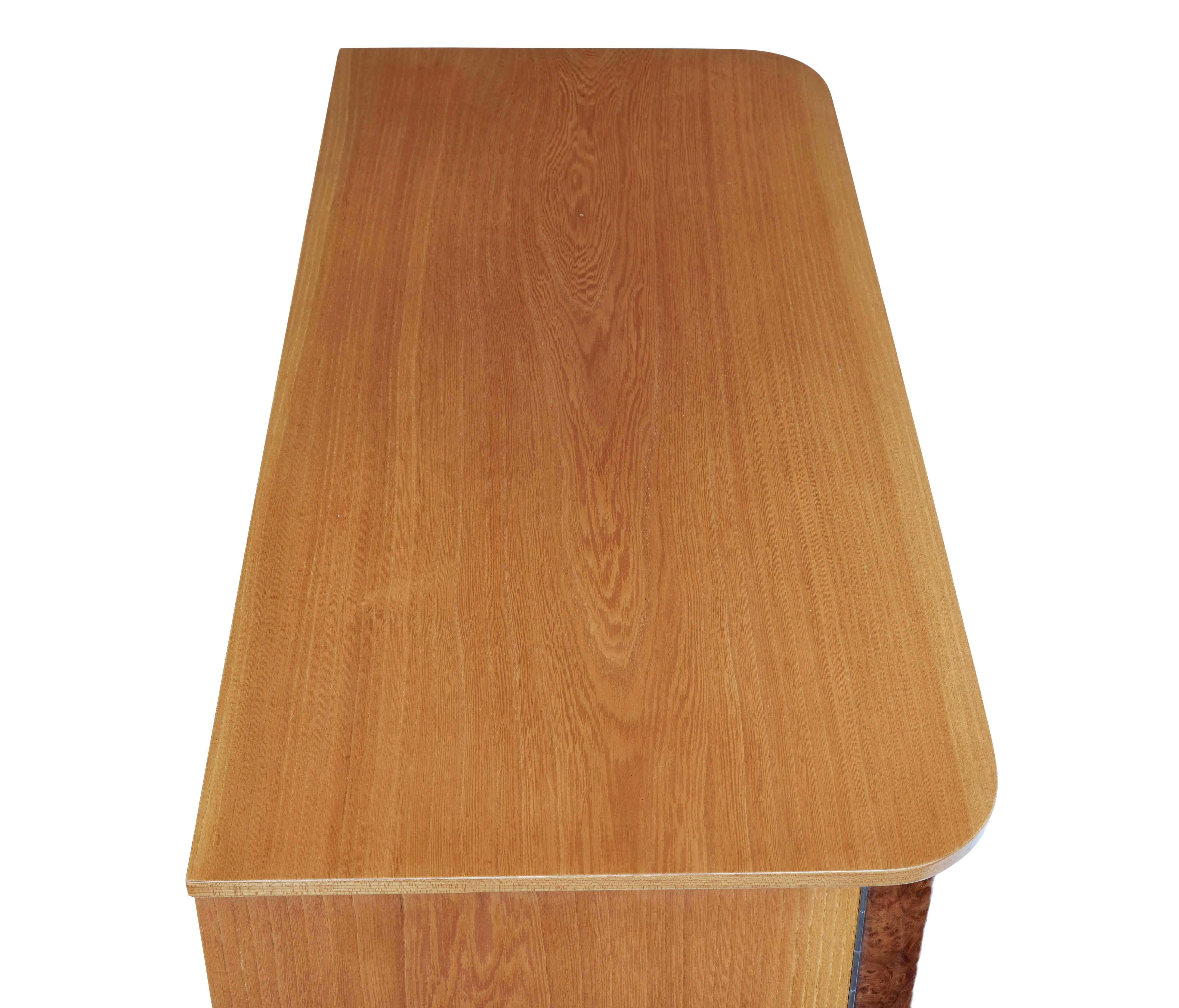 Swedish mid 20th century elm and burr fitted chest of drawers circa 1960.

Stunning chest of drawers with fitted side compartments.  Veneered in rich elm with 3 central graduating drawers with turned handles, flanked each side by a shaped burr door