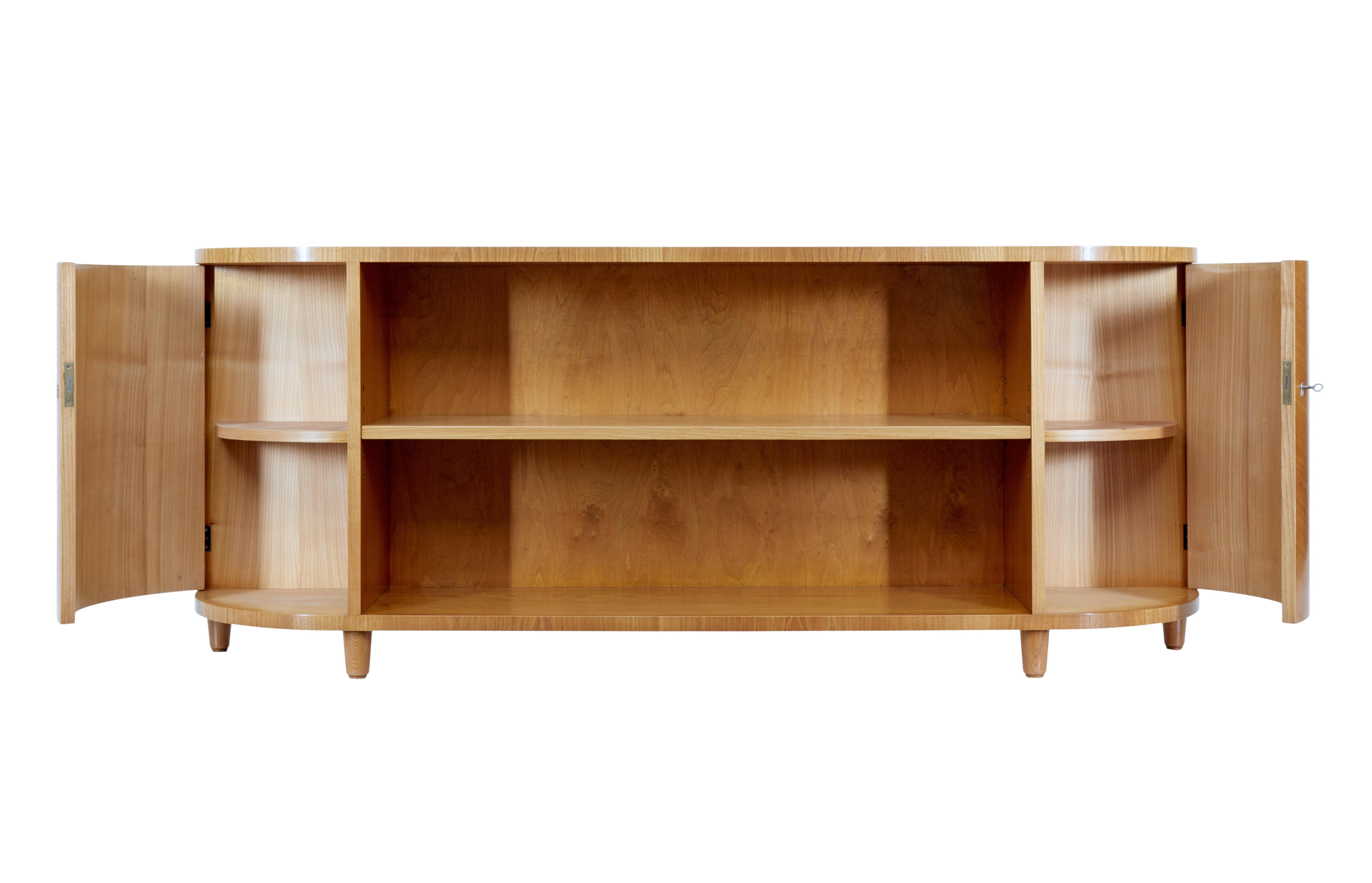 Swedish mid 20th century elm low open bookcase circa 1950.

Fine elegant piece of mid century Swedish furniture. Central book or display adjustable shelf which is flanked either side by a shaped cupboard which opens on the key. Each cupboard