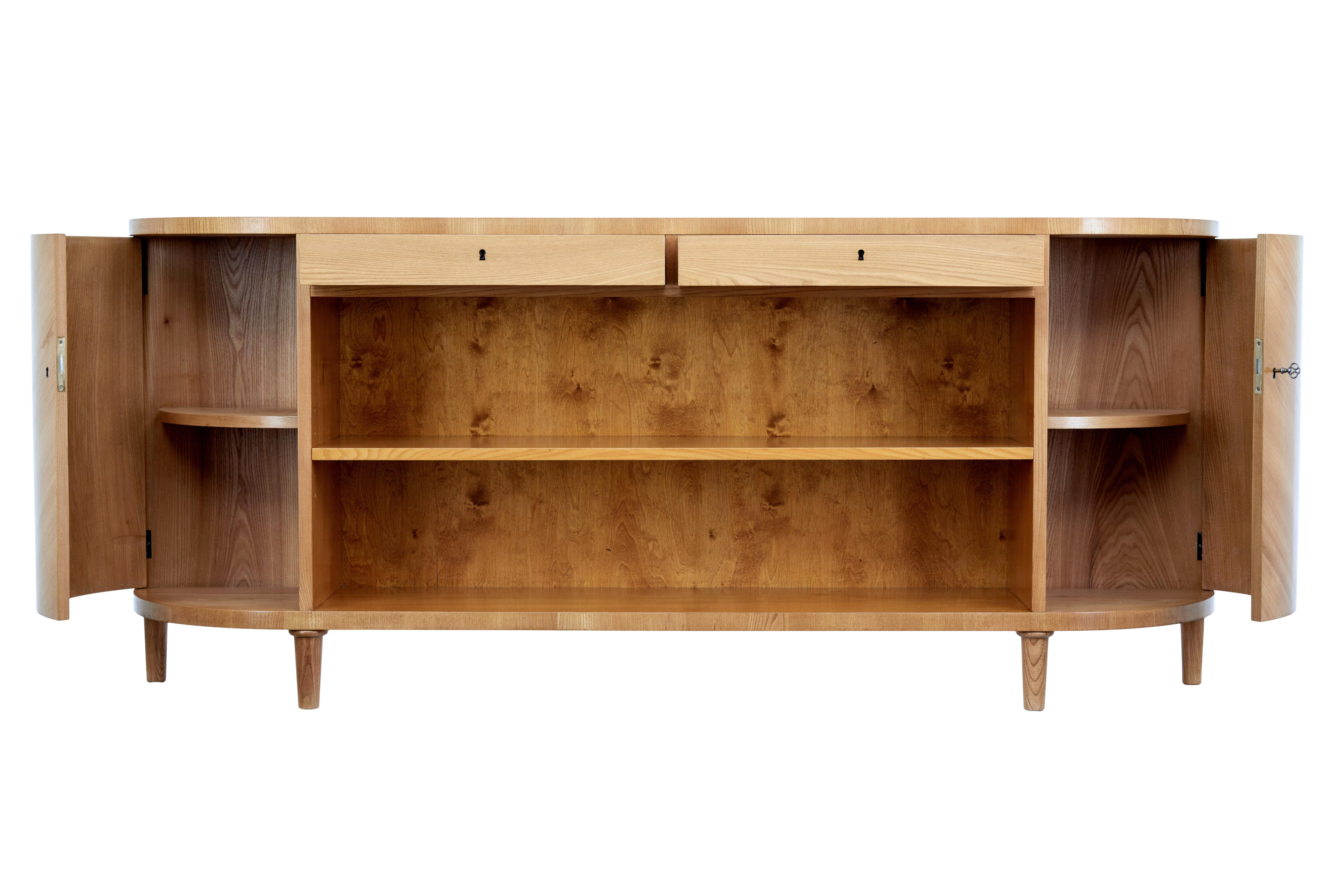 Swedish mid 20th century low sideboard with bookcase circa 1950.

Superb example of Swedish design for maximum storage. Beautifully shaped ends and veneered in elm allover. 2 drawers directly below the top surface with working locks and key. Main