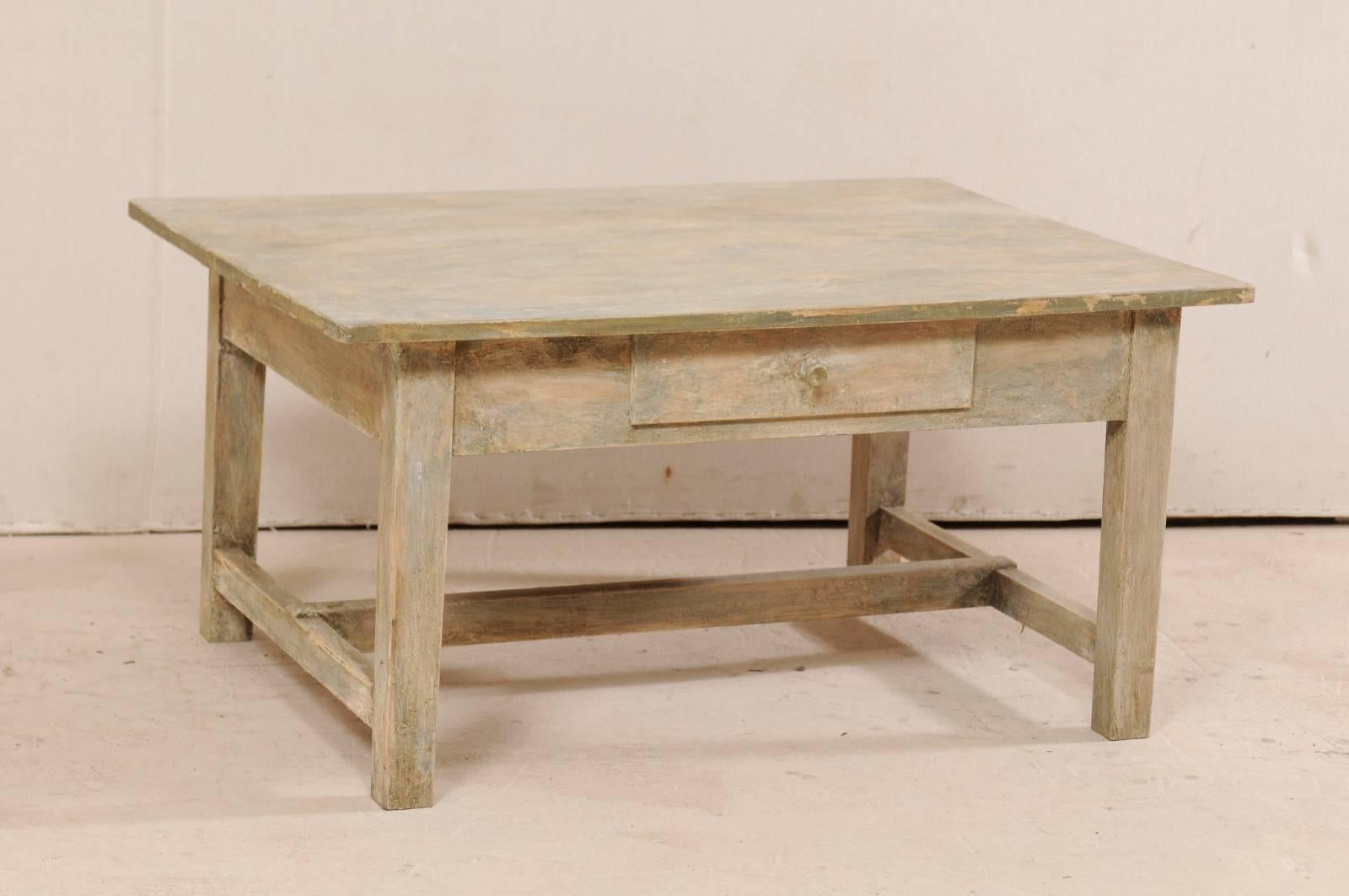 A Swedish mid-20th century painted wood coffee table. This mid-century table from Sweden features a rectangular-shape, overhanging top, straight skirt, and is raised up on squared legs. There is a single drawer set within the skirt at center, a