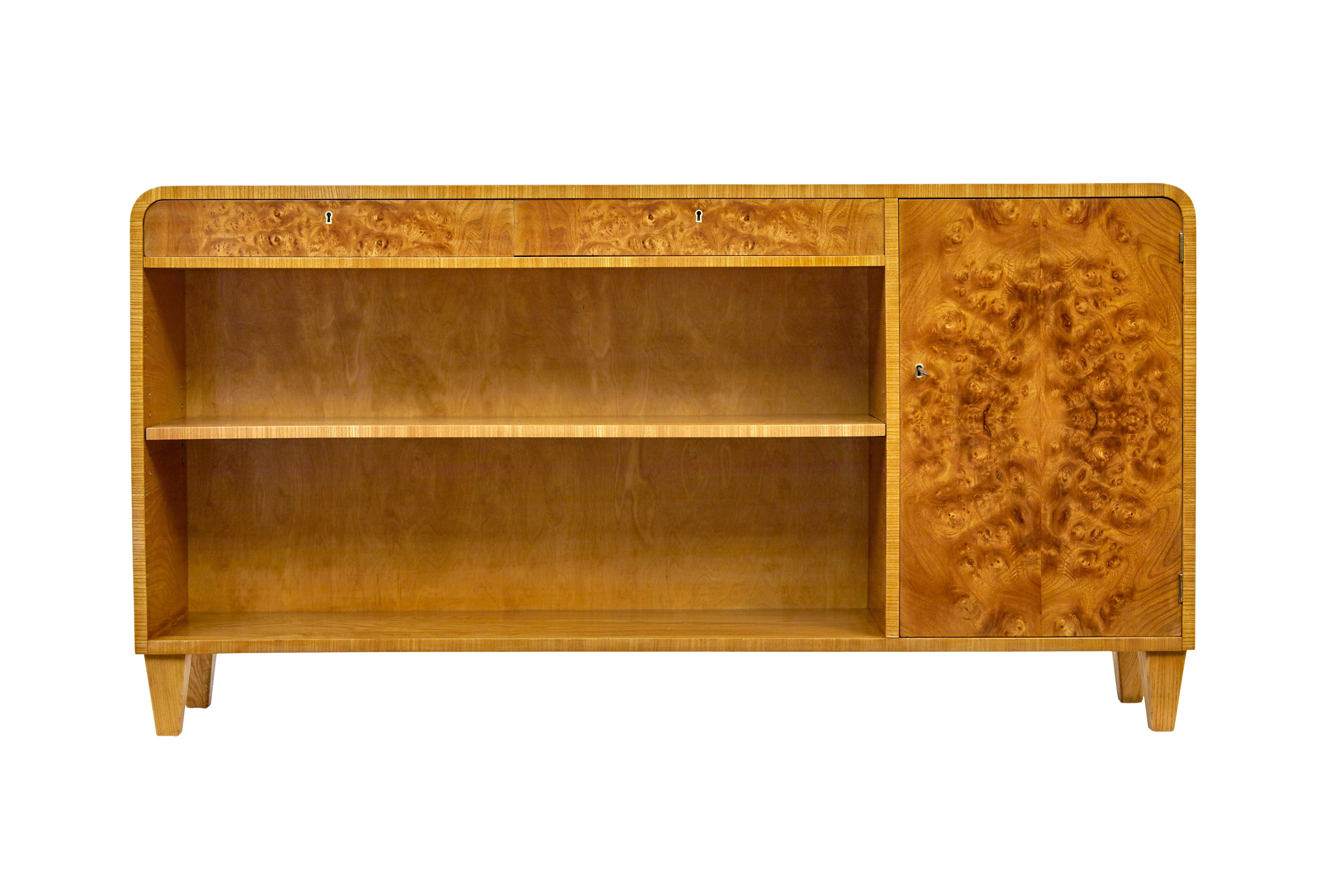 Bibliothèque ouverte basse en loupe d'orme suédoise du milieu du siècle, vers 1950.

Bel exemple de qualité de ce type de bibliothèque, qui se prête à de nombreuses pièces de la maison.

Côtés et dessus en placage d'orme avec coins arrondis. Sous la