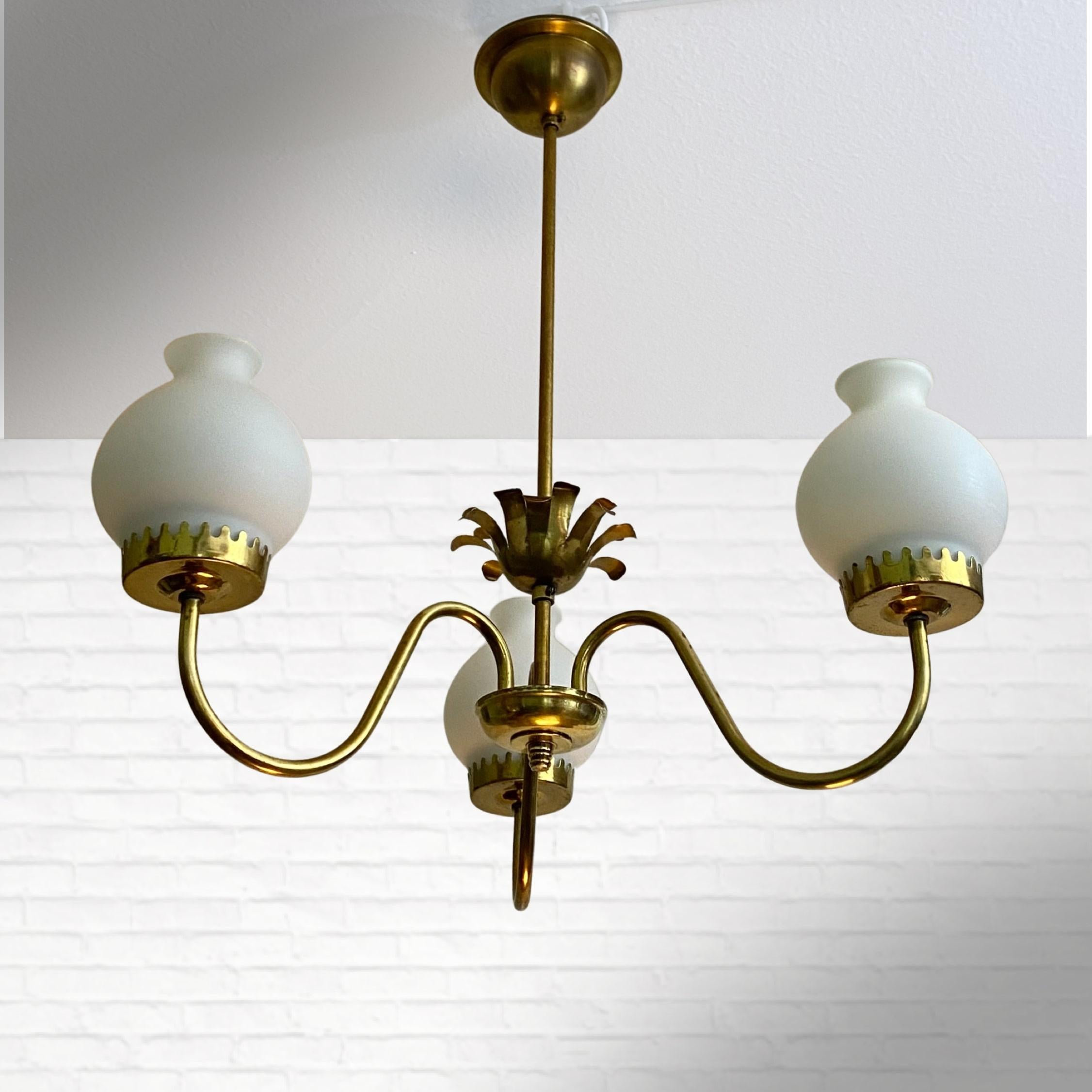 Swedish 1940s chandelier made from brass with three curved arms holding bell-shaped shades in opal glass. The centered flower-shaped decoration brings some extra elegance to this graceful fixture. With its minimalistic shape and clean lines, this