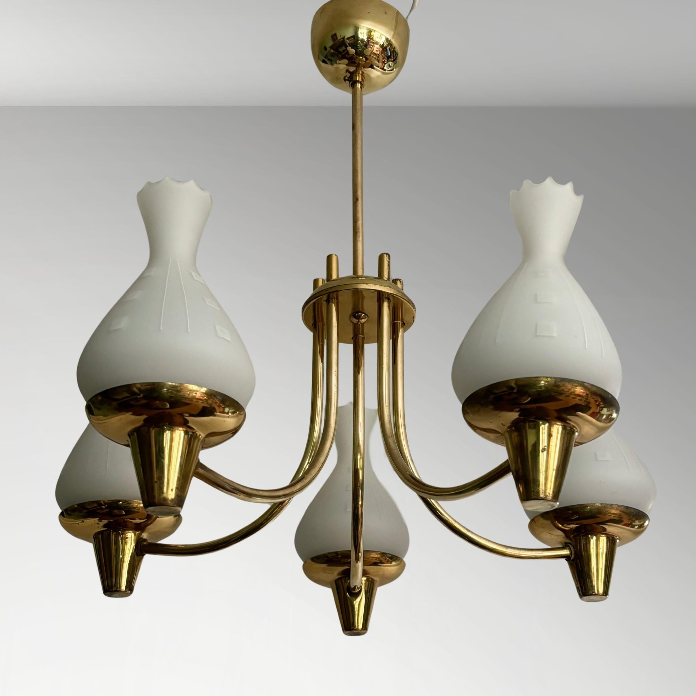 Un lampadario svedese di buon gusto realizzato in ottone, con cinque bracci curvi che sorreggono paralumi di forma organica in vetro opalino. Prodotto da un produttore non identificato negli anni '40, questo lampadario è un bellissimo esempio