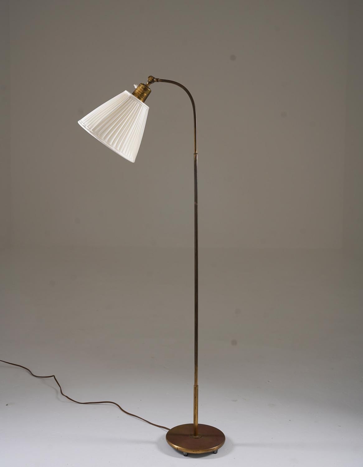 Ce lampadaire raffiné des années 1940, produit par Nordiska Kompaniet, témoigne du savoir-faire exquis et de l'élégance discrète de l'époque. La lampe est dotée d'un cadre en laiton élancé et gracieusement arqué, à la fois robuste et visuellement