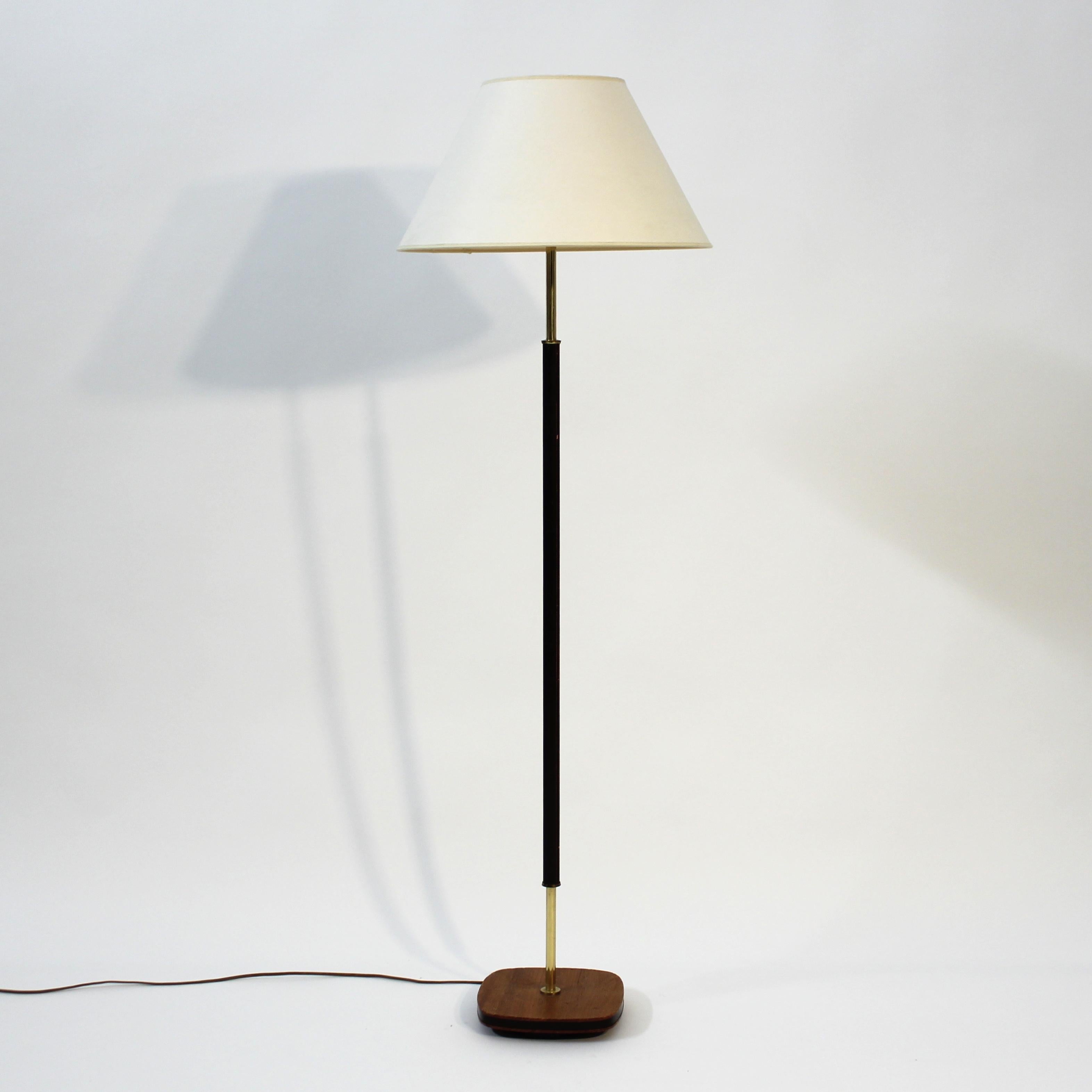 Swedish mid-century floor lamp with leather covered brass stem, mounted on a teak base. Beige/white shade. Good and honest vintage condition with light ware consistent with age and use.