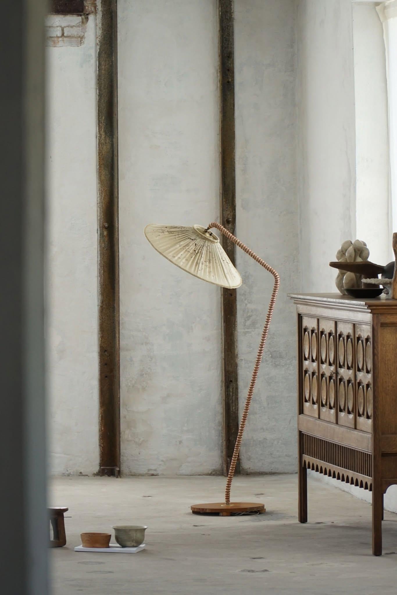An elegant example of Scandinavian design from the 1950s, this sculptural curved floor lamp beautifully embodies the principles of Swedish Mid-Century Modernism. The lamp features a graceful frame upholstered in textile with a delicately
