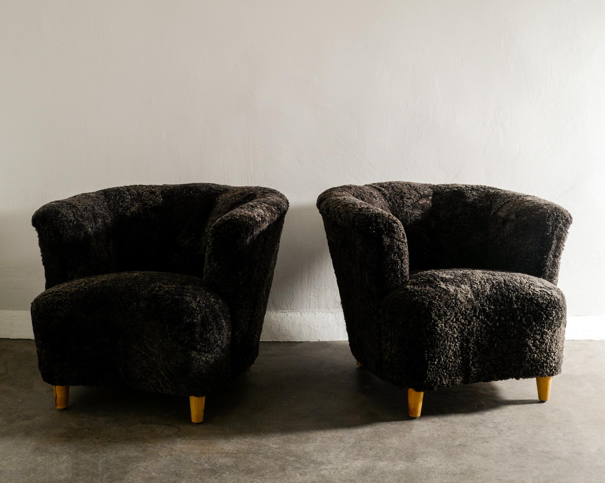 Rare pair of Swedish mid century modern armchairs with a nice curved back.  Fully and professionally restored and newly upholstered in a dark grey sheepskin. 

Dimensions: H: 68 cm W: 84 cm D: 90 cm SH: 44 cm .
